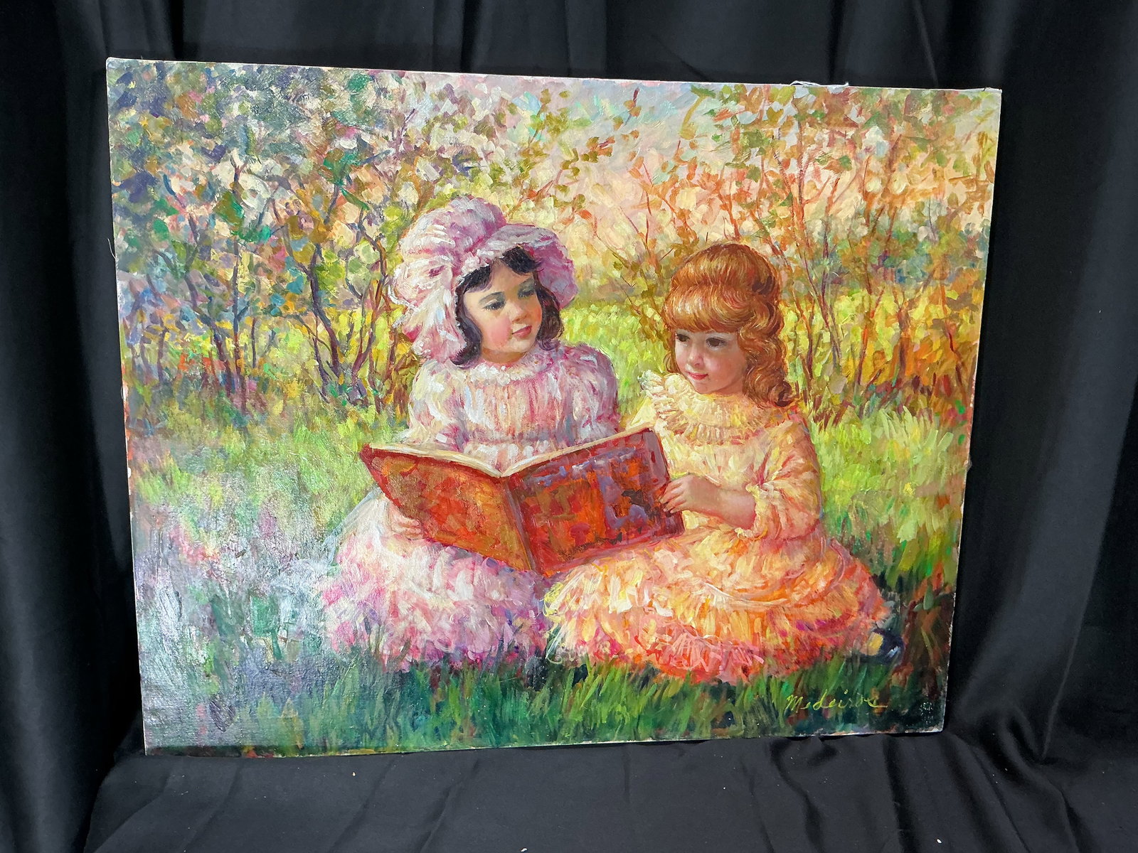 "2 Girls with Book" Oil Painting Signed Myrle Medeiros: An original oil painting on canvas depicting two young girls seated in a sunlit meadow, reading from an open book. Rendered in vivid impressionist brushwork with warm pastel tones and dappled foliage.