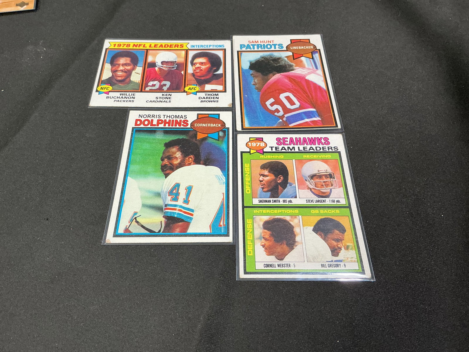 1978-79 Topps Football Card Lot Leaders Stars Checklist: Group of four vintage Topps football cards including 1978 NFL Leaders Interceptions card (Willie Buchanon, Ken Stone, Thom Darden), Sam Hunt Patriots, Norris Thomas Dolphins, and Seattle Seahawks Team