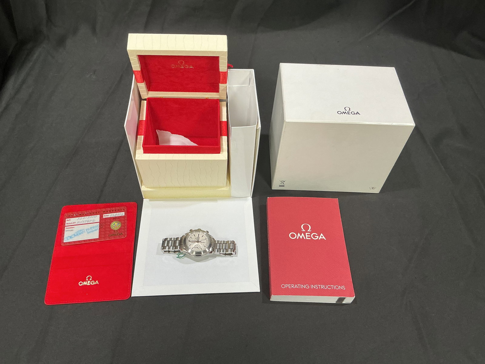 Omega Speedmaster Chronograph Wristwatch Full Set Box Papers: Omega Speedmaster stainless steel chronograph wristwatch presented with original inner and outer boxes, warranty card, and operating manual. Classic multi-subdial chronograph layout with tachymeter be