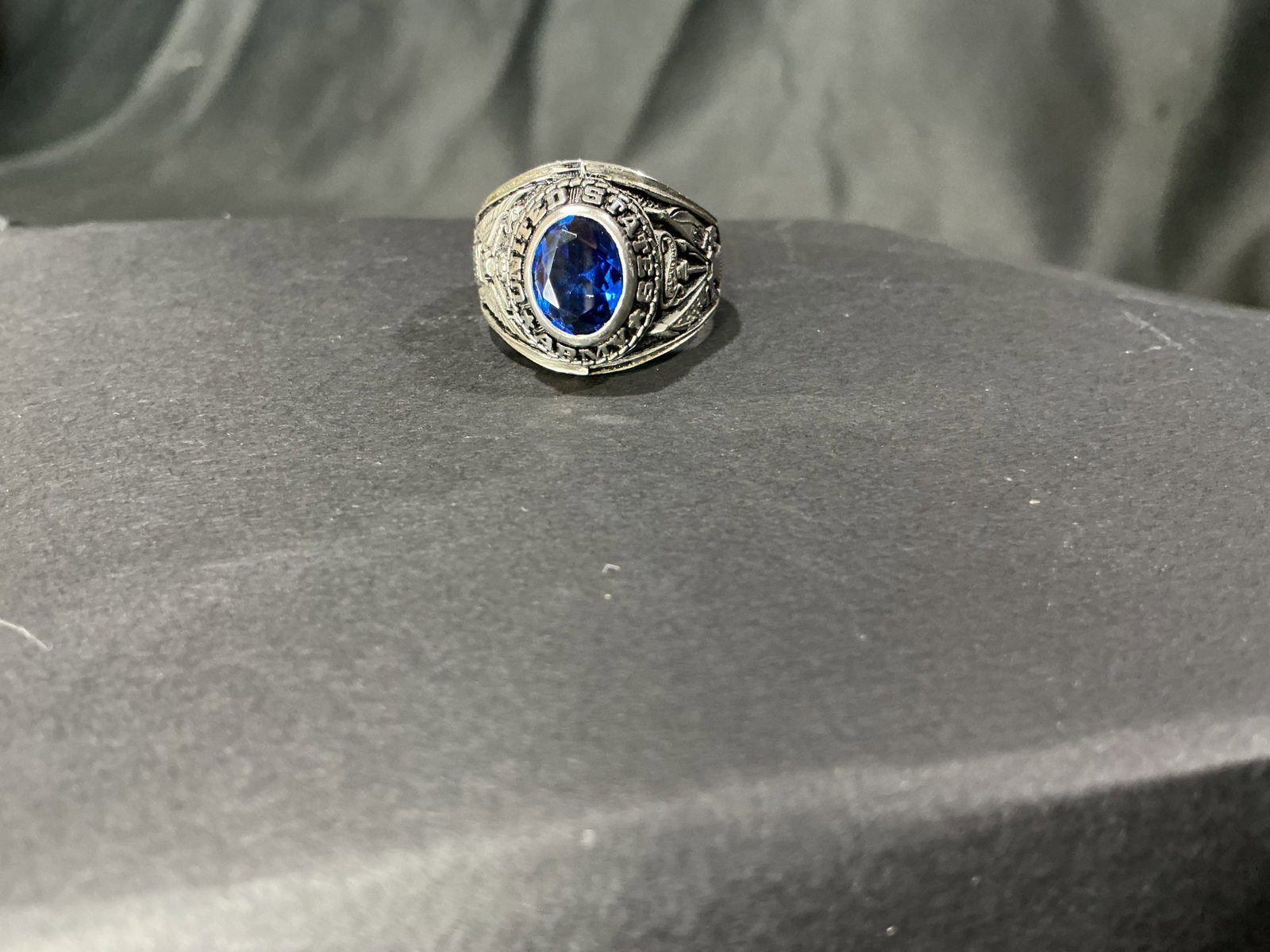 United States Army Blue Stone Commemorative Ring: United States Army themed commemorative ring featuring blue faceted center stone with military style iconography and detailed silver tone mounting. Decorative military collectible with bold presentati