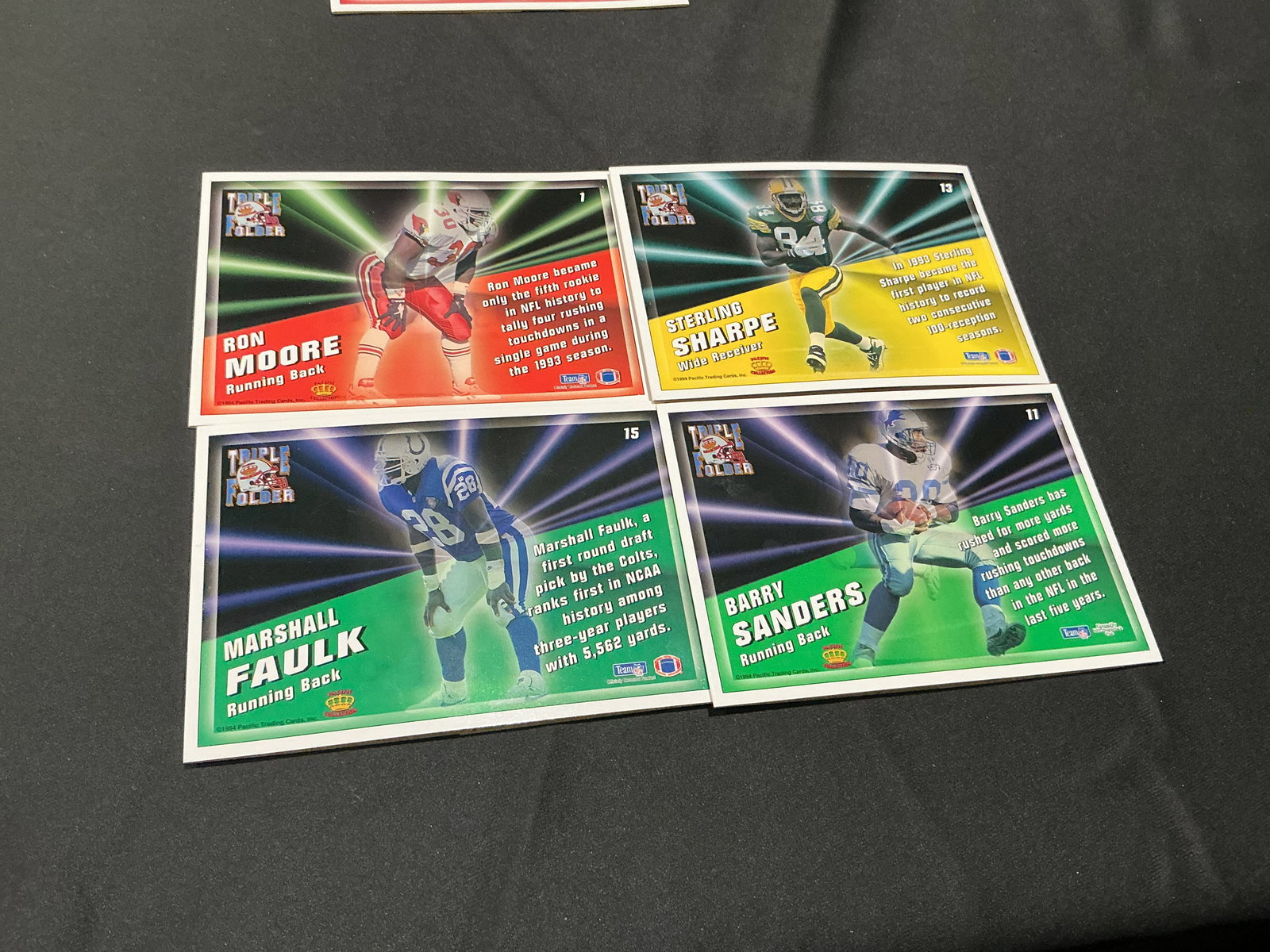 1994 Pacific Triple Folders Barry Sanders Faulk Sharpe: 1994 Pacific Triple Folders NFL card lot featuring Barry Sanders, Marshall Faulk, Sterling Sharpe, and Ron Moore. Interactive fold-out card format with colorful mid-1990s football design and multiple 