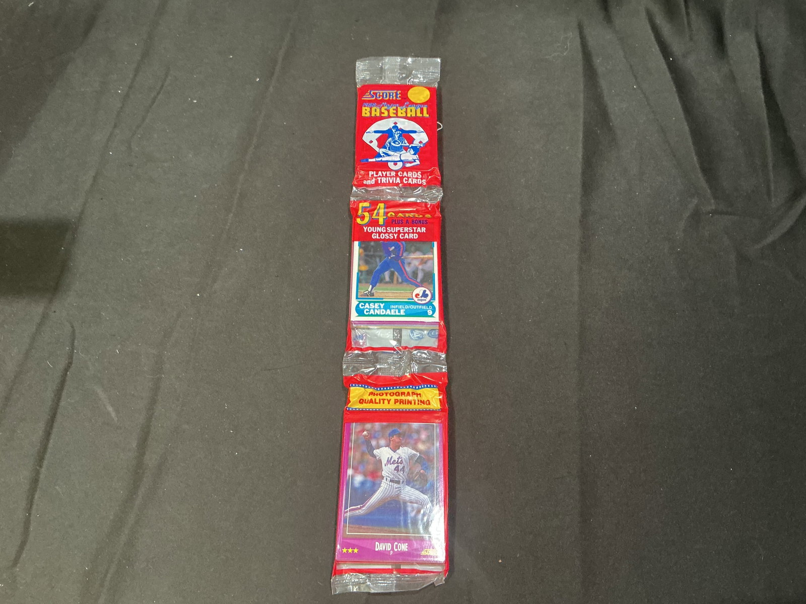 1990 Score Baseball Wax Pack David Cone Bonus Card: Sealed 1990 Score Baseball wax pack containing 54 player and trivia cards plus bonus young superstar glossy card featuring David Cone on packaging. Vintage unopened baseball card pack with strong nost