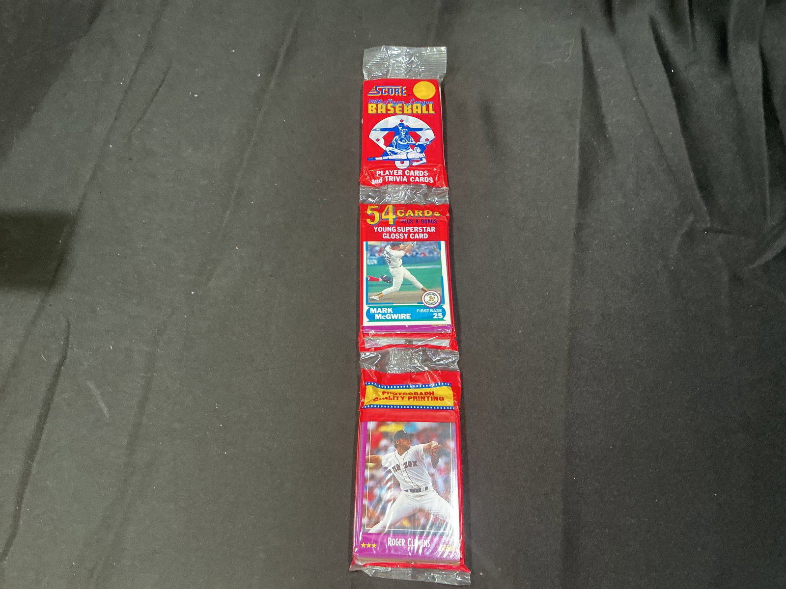 1990 Score Baseball Wax Pack Roger Clemens Bonus Card: Sealed 1990 Score Baseball wax pack featuring Roger Clemens bonus glossy superstar card and Mark McGwire packaging artwork. Includes 54 cards plus bonus glossy insert with strong appeal for vintage ba