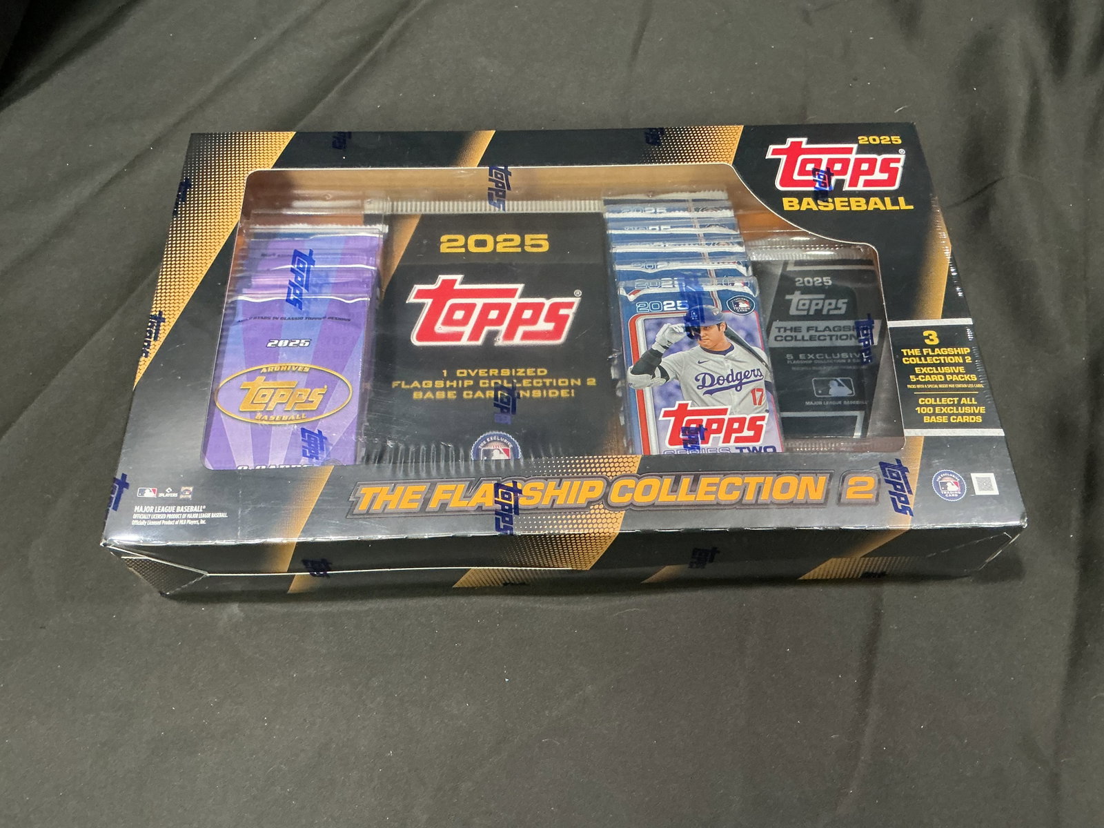2025 Topps Baseball Flagship Collection Factory Sealed Box: Factory sealed 2025 Topps Baseball Flagship Collection box featuring exclusive packs, oversized card content, and collectible modern baseball card presentation. Strong chase and rip appeal for