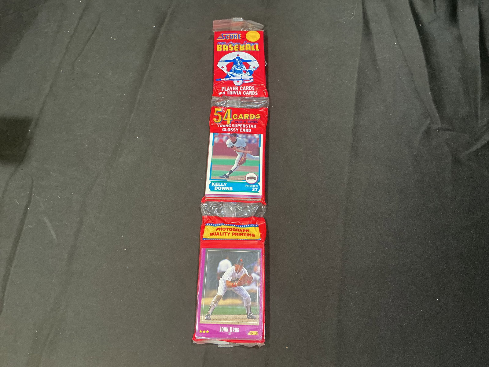 1990 Score Baseball Wax Rack Pack Kelly Downs John Kruk: Vintage 1990 Score Baseball rack pack featuring Kelly Downs and John Kruk visible on the wrapper cards. Includes 54 cards plus bonus glossy card from the colorful early 1990s Score baseball release.