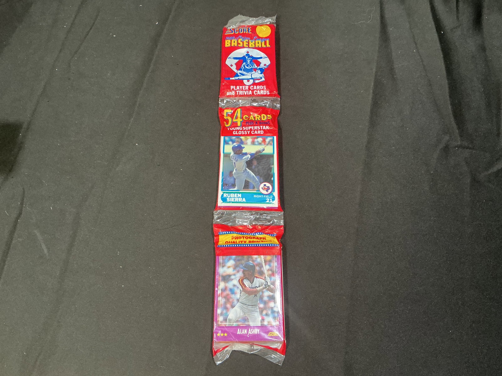 1990 Score Baseball Wax Pack Ruben Sierra Alan Ashby: Vintage sealed 1990 Score Baseball wax pack featuring Ruben Sierra and Alan Ashby on the wrapper panels. Includes 54 cards plus bonus young superstar glossy card. Early 1990s baseball release with sta
