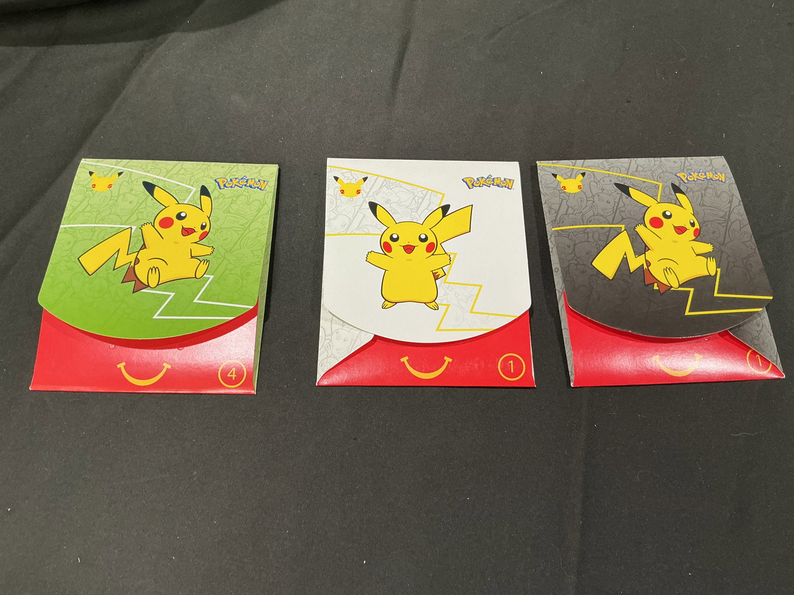 Pokemon McDonalds Promo Pack Trio Sealed Happy Meal Packs Returning Favorite: Group of three sealed Pokemon McDonalds Happy Meal promotional card packs with variant Pikachu packaging colors. Includes sealed promo packs featuring classic starter artwork presentation and
