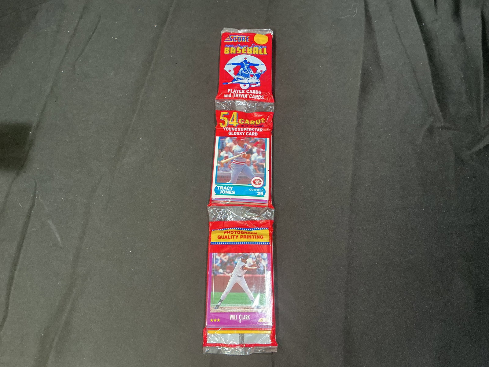1988 Score Baseball Wax Pack Sealed 54 Card Rack Pack Will Clark: Factory sealed 1988 Score Baseball rack pack containing 54 cards plus glossy young superstar card. Visible stars include Will Clark and Tracy Jones on front panels. Colorful late-1980s baseball releas