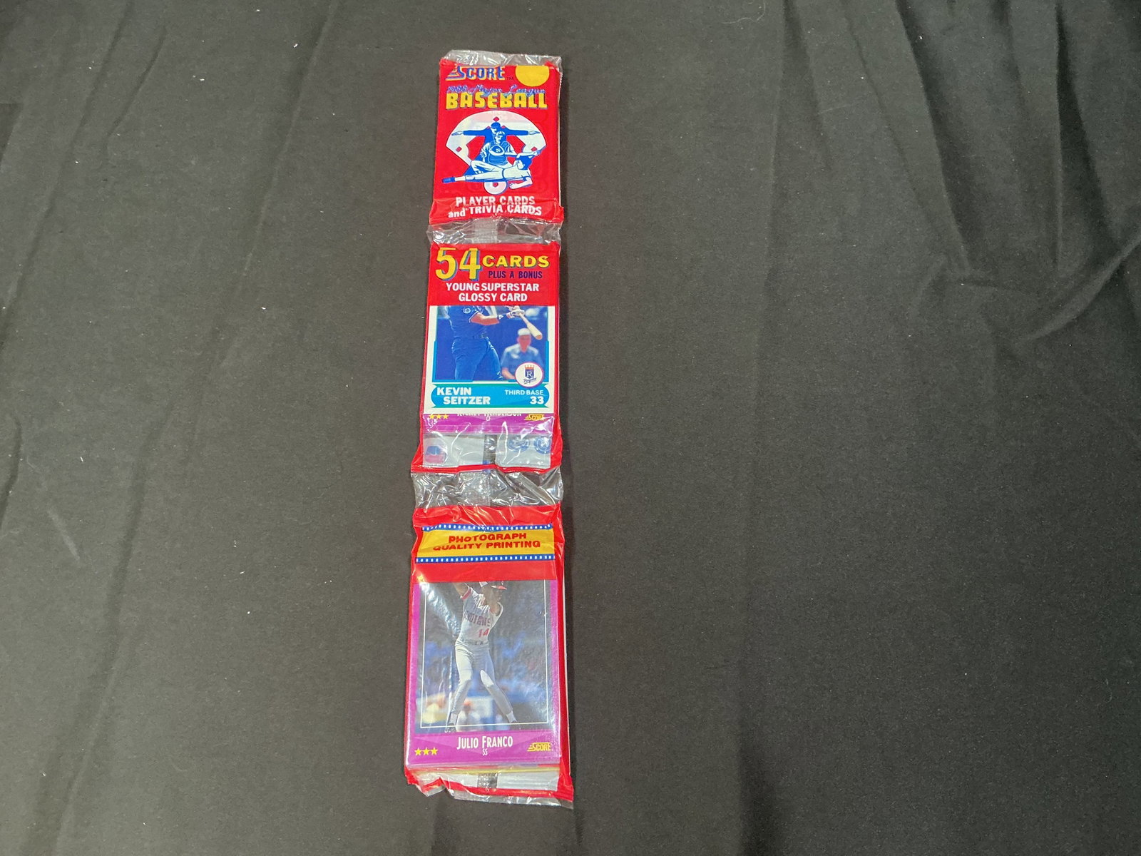 1988 Score Baseball Sealed 54 Card Rack Pack Kevin Seitzer: Factory sealed 1988 Score Baseball rack pack containing 54 cards plus glossy young superstar insert card. Visible players include Kevin Seitzer and Julio Franco on front panels. Popular late-1980s bas
