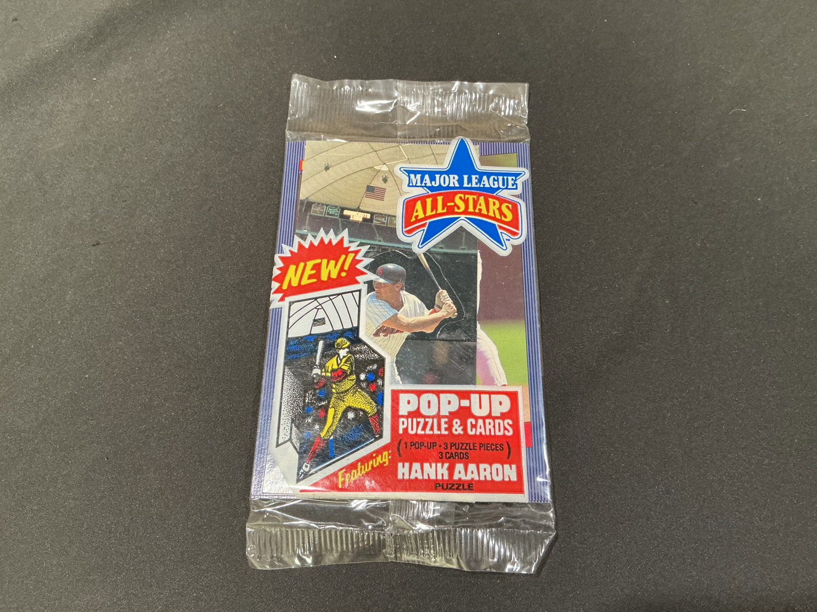 Major League All-Stars Hank Aaron Sealed Puzzle & Cards Pack: Vintage sealed Major League All-Stars puzzle and cards pack featuring Hank Aaron artwork and pop-up puzzle insert. Includes three trading cards, three puzzle pieces, and pop-up feature inside sealed o