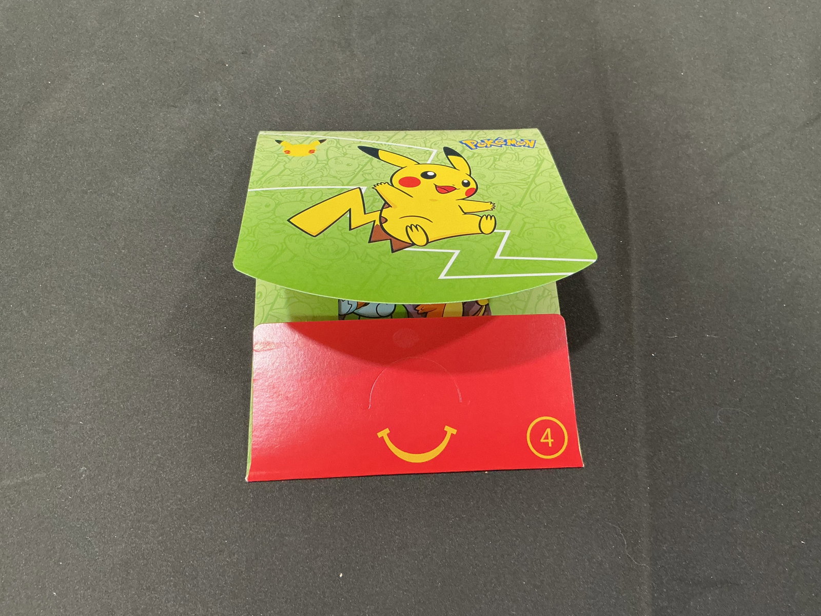 Pokemon McDonalds Pikachu Happy Meal Box Collectible: Returning Pokemon McDonalds Pikachu Happy Meal box collectible with green variation artwork and playful Pokemon themed presentation. Fun crossover collectible with display appeal for Pokemon fans and 