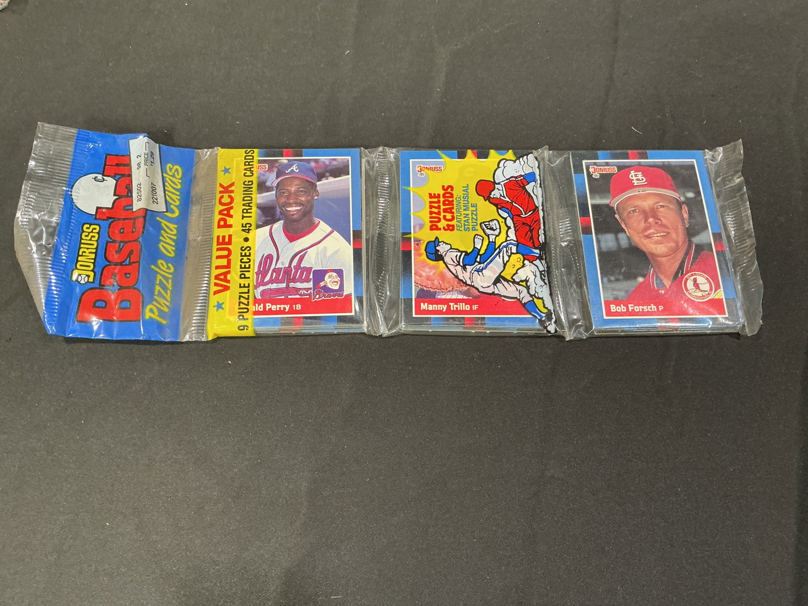 1990 Donruss Baseball Value Pack Sealed Puzzle & Cards: Factory sealed 1990 Donruss Baseball value pack featuring 45 cards and puzzle pieces with visible players including Gerald Perry, Manny Trillo, and Bob Forsch. A nostalgic unopened wax-era baseball re