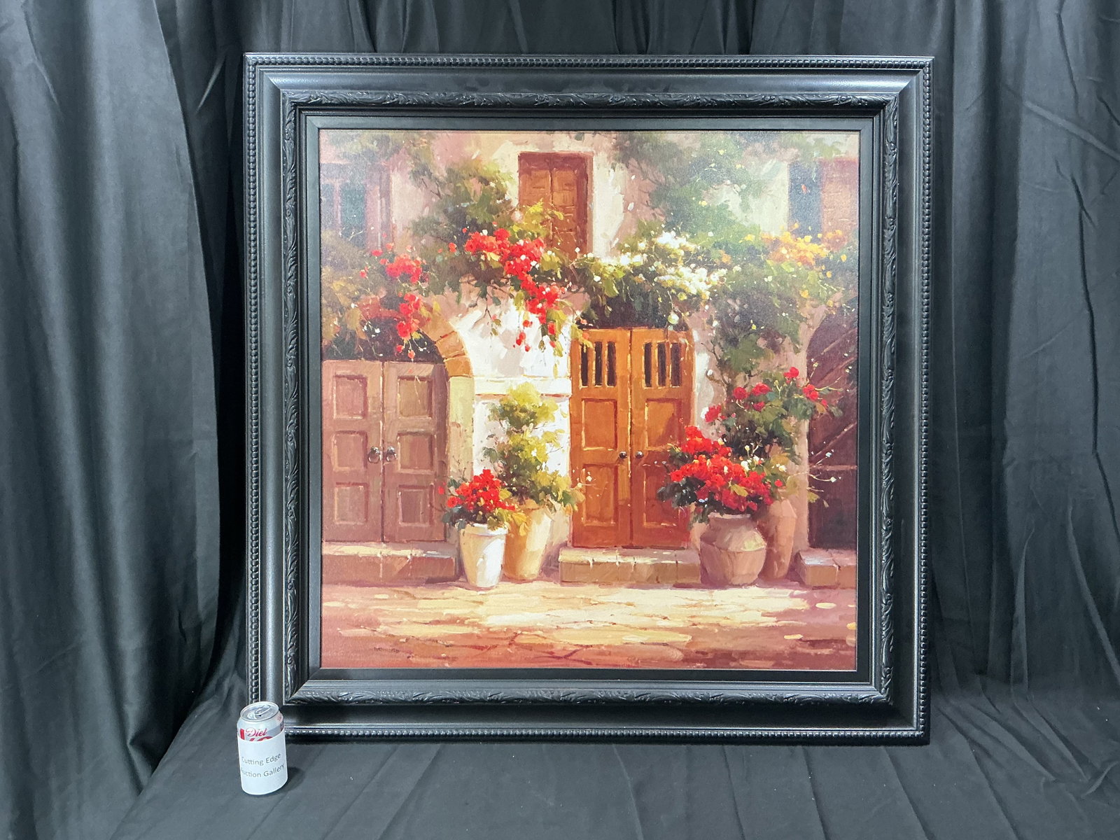Large Framed Courtyard Floral Scene Oil Painting: Large framed decorative oil painting depicting a sunlit courtyard scene with flowering plants, rustic doors, and Mediterranean-inspired architecture. Rich warm tones and textured brushwork create