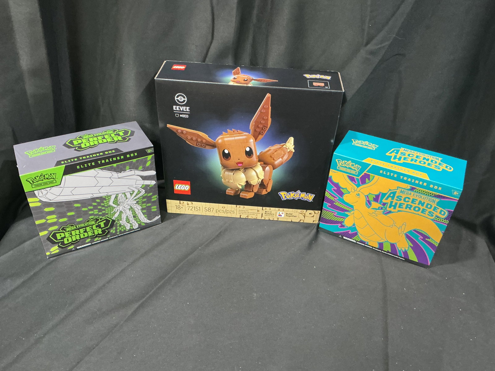 Pokemon ETB & LEGO Eevee Collector Lot Factory Sealed: Collector grouping featuring a sealed Pokemon Mega Evolution Perfect Order Elite Trainer Box, sealed Mega Evolution Ascended Heroes Elite Trainer Box, and LEGO Pokemon Eevee Set 72151 containing 587 p