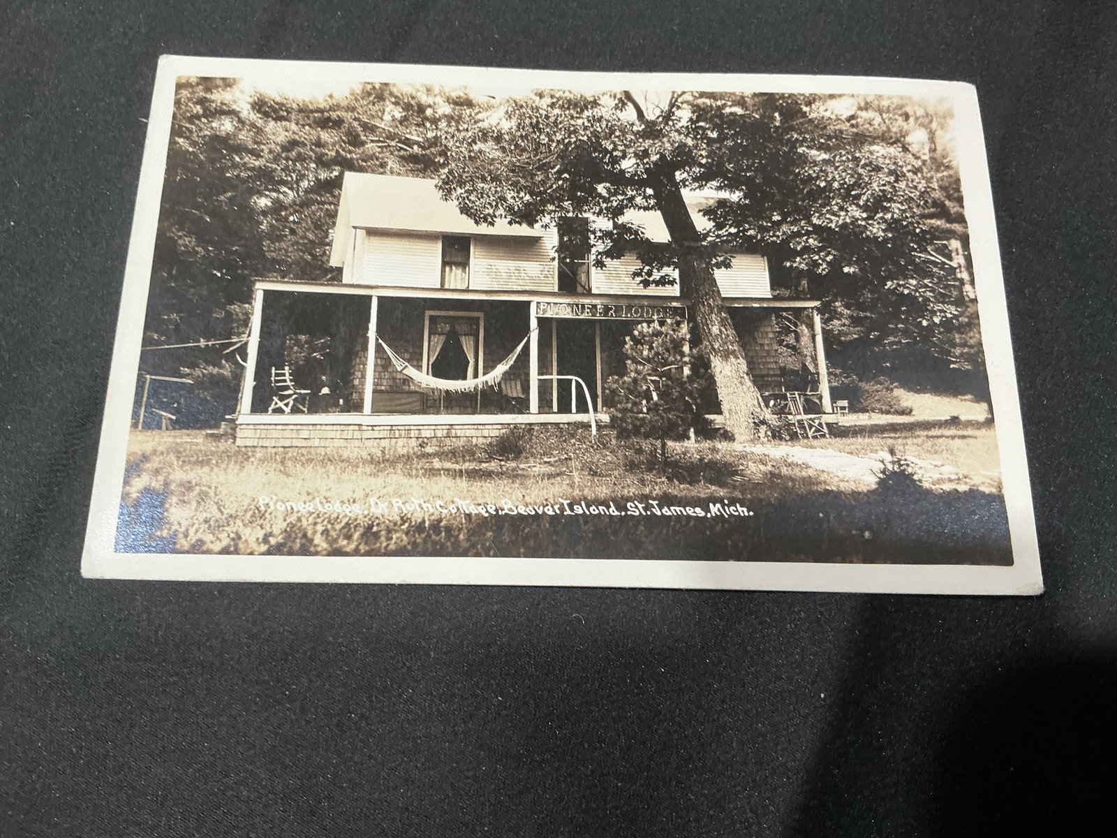 Pioneer Lodge Beaver Island MI Postcard: Vintage real photo postcard featuring Pioneer Lodge on Beaver Island, St. James, Michigan. Scenic lodge view with porch hammock and period architecture. Unused postcard with divided back and strong