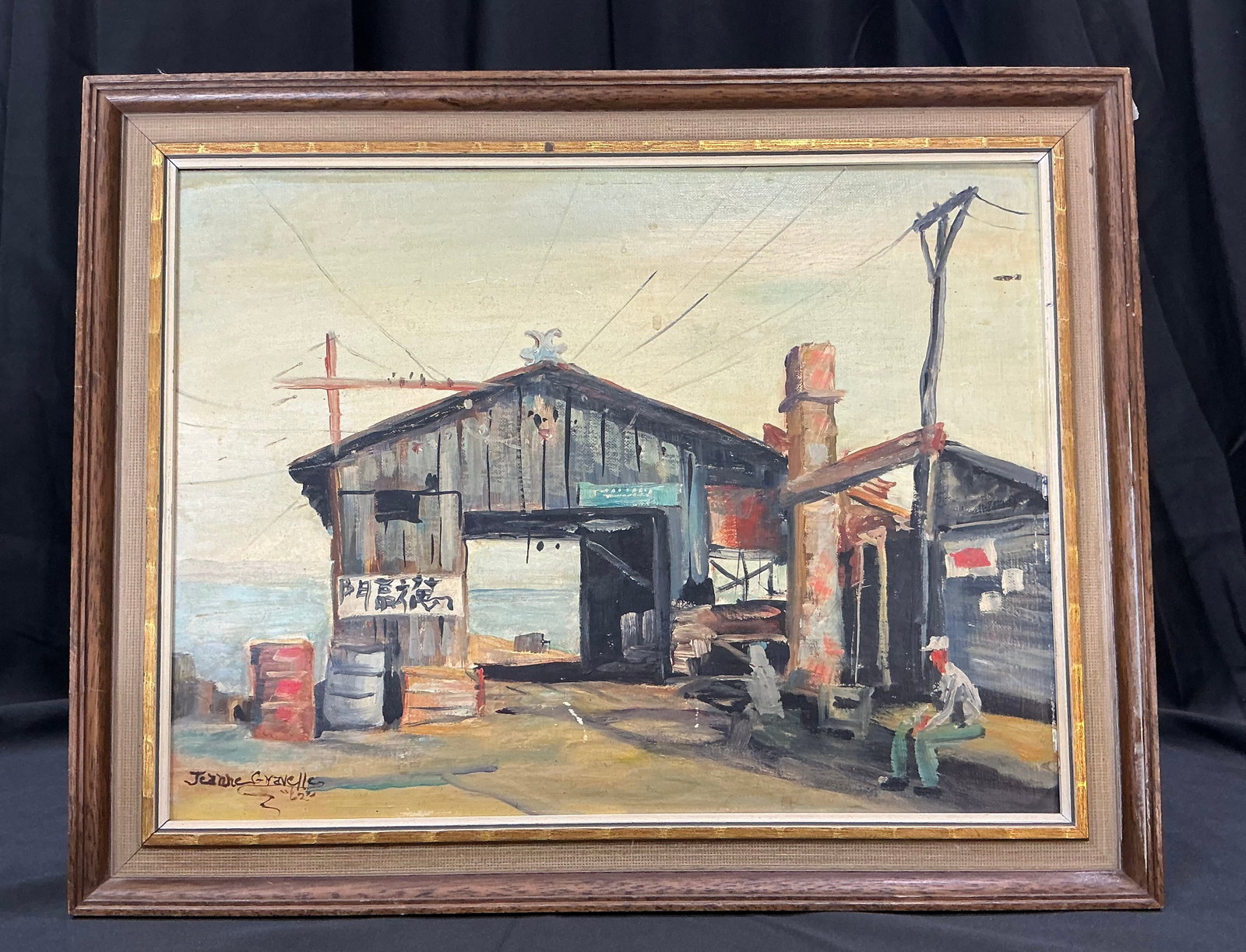 Jeanne Gravelle 1962 Harbor Oil Painting: Signed and dated 1962, this original framed oil painting by Jeanne Gravelle depicts a rustic waterfront harbor scene with weathered buildings, utility poles, and a seated figure overlooking the