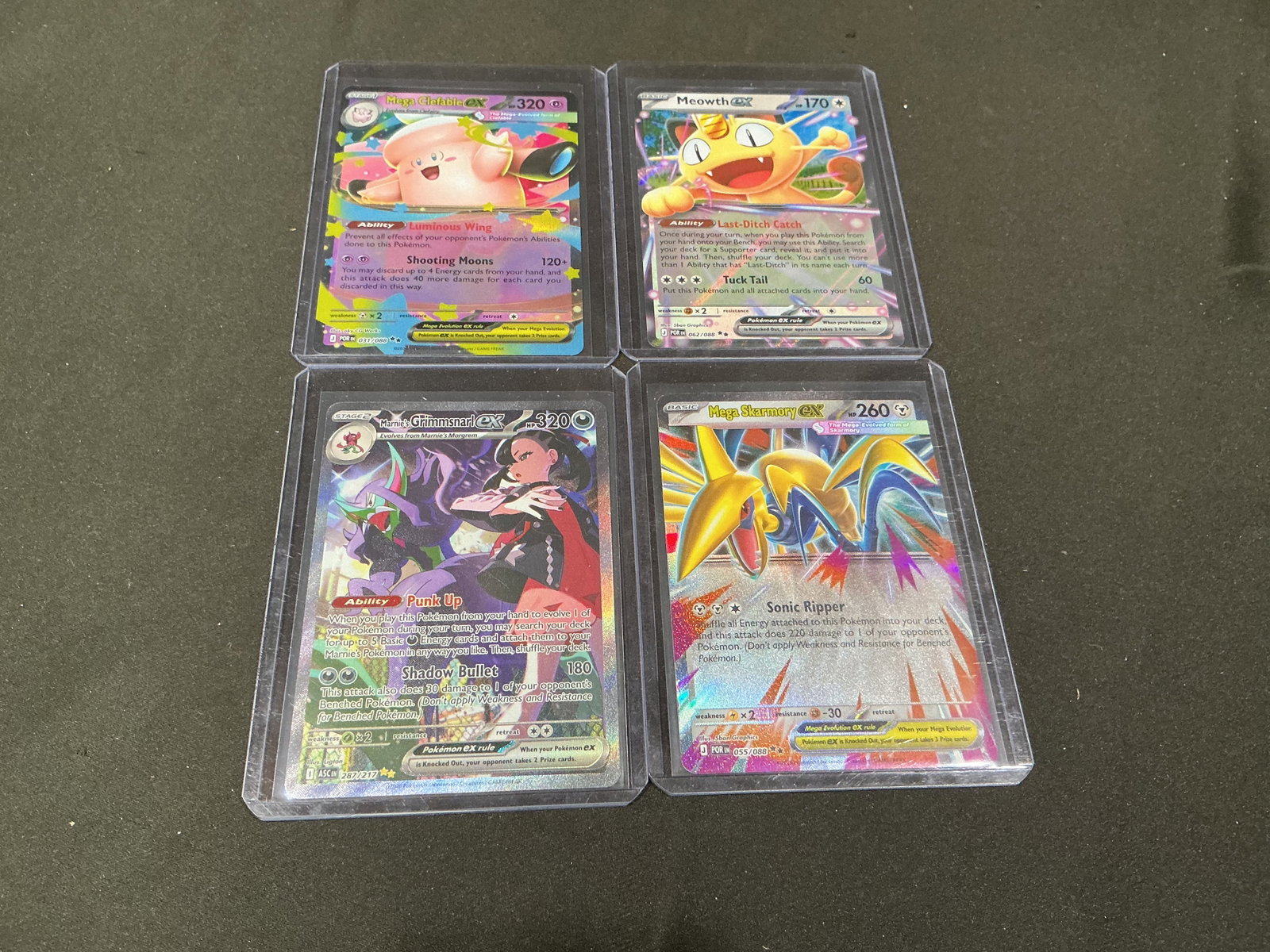 Pokemon Full Art Card Lot: Four-card Pokemon full art lot featuring Mega Clefable EX, Meowth ex, Marnie's Grimmsnarl ex, and Mega Skarmory EX. A colorful mix of modern full art and Mega Evolution-era style cards assembled for