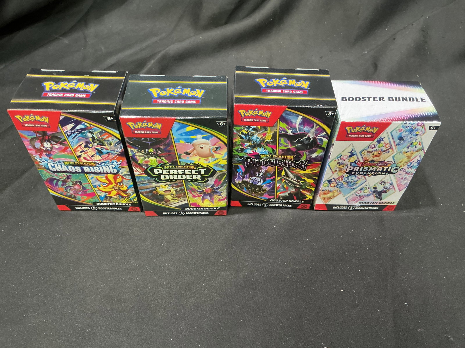 Booster Bundle 4 Collection Set: Bringing together four factory sealed Pokemon Booster Bundles, this collection includes Chaos Rising, Perfect Order, Pitch Black, and Prismatic Evolutions. A diverse assortment spanning multiple popul
