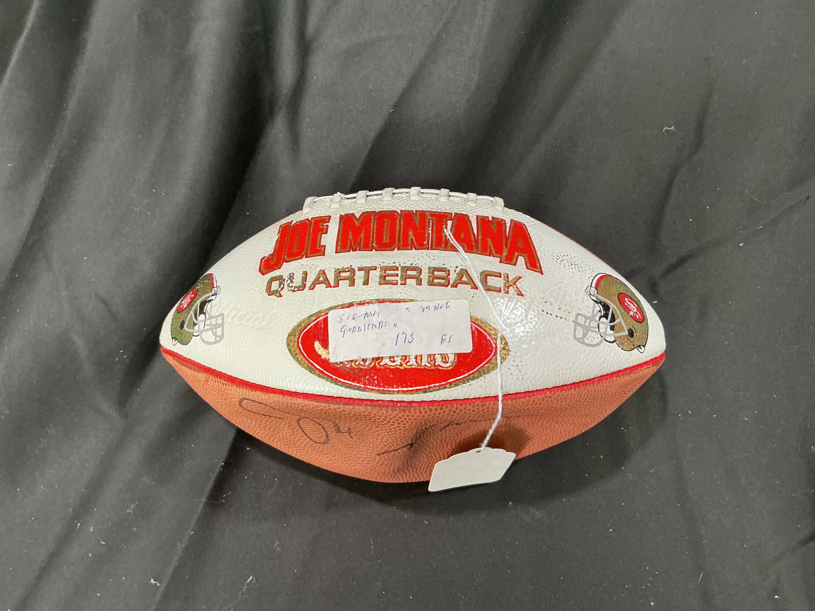 Joe Montana Signed Wilson Football: Wilson NFL football signed by Hall of Fame quarterback Joe Montana featuring a themed San Francisco 49ers 'Joe Montana Quarterback' display panel. Despite visible age-related wear to the decorative