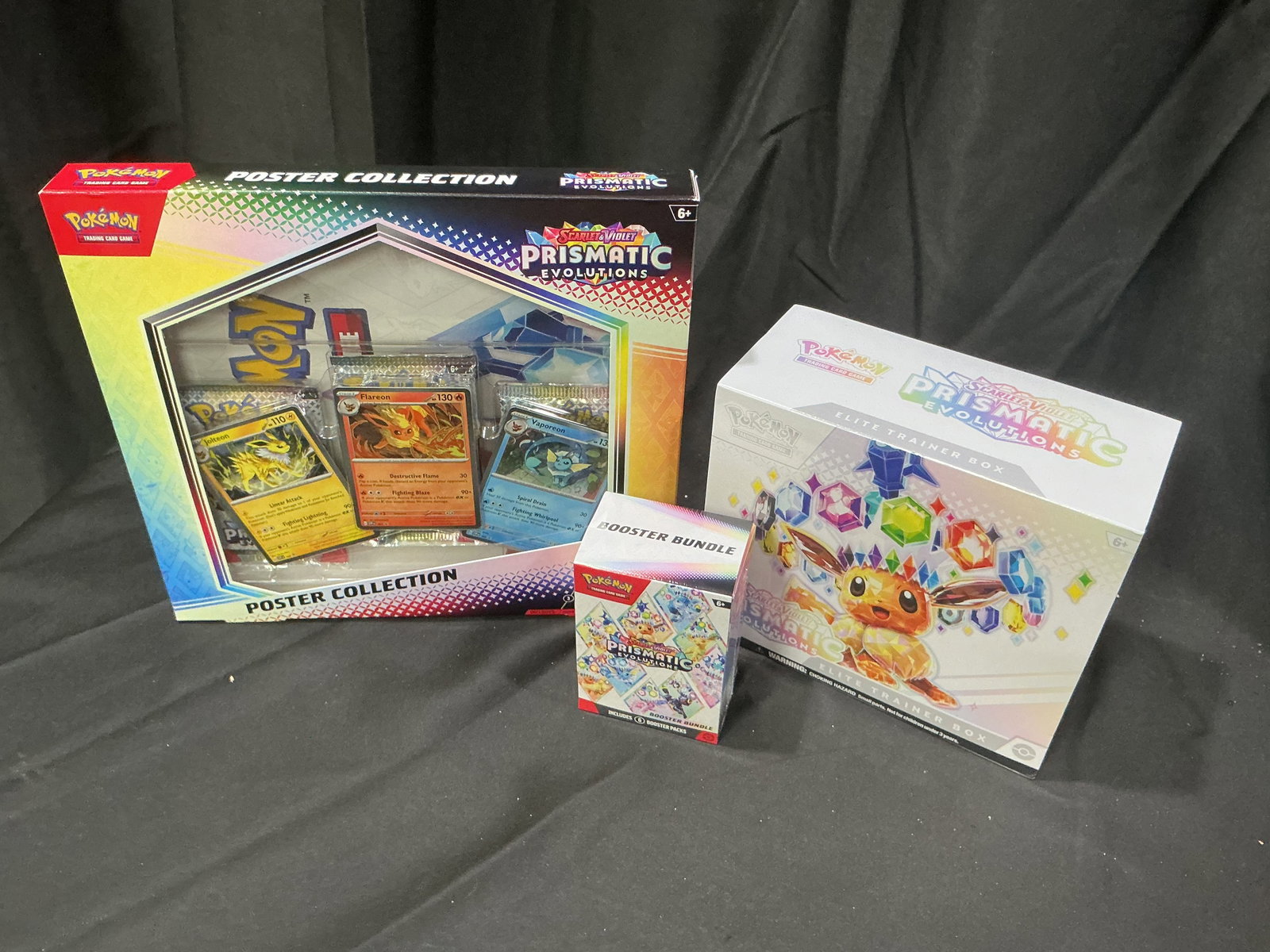 Prismatic Evolutions Triple Bundle: Returns after prior appearance, this factory sealed Pokemon Prismatic Evolutions grouping includes one Elite Trainer Box, one Booster Bundle, and one Poster Collection together in a premium sealed lot
