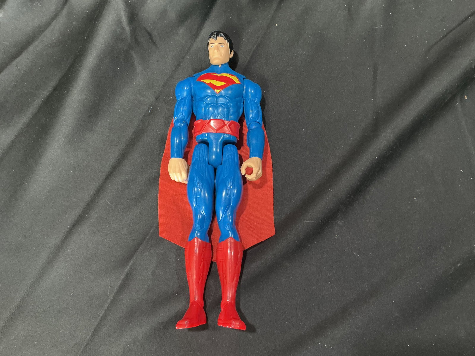 DC Superman Figure Cloth Cape: Returns after prior appearance, DC Comics Superman action figure produced by Mattel featuring the classic blue suit with red and yellow chest emblem, red belt, red boots, and attached red cloth cape. 