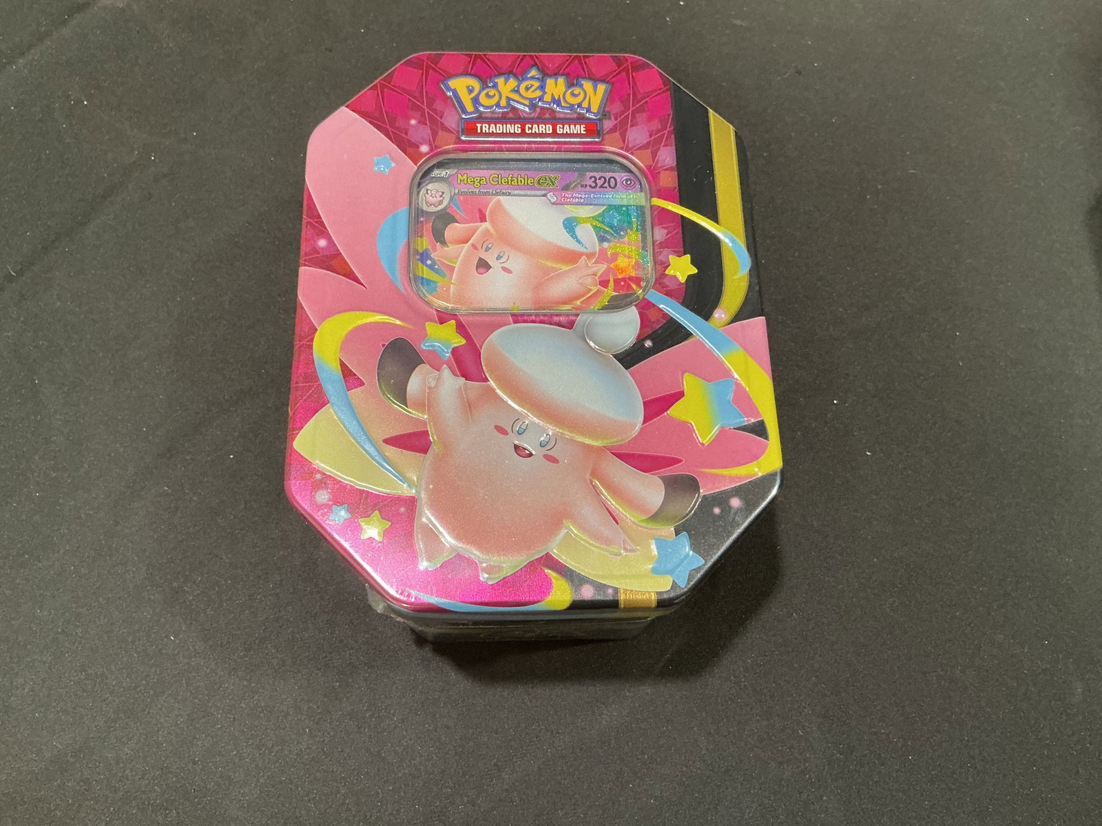Mega Clefable ex Moonlit Tin: Making another appearance in this auction, this factory sealed Pokemon Mega Moonlit Tin features a Mega Clefable ex promo card and four Pokemon TCG booster packs. The compact tin format, colorful