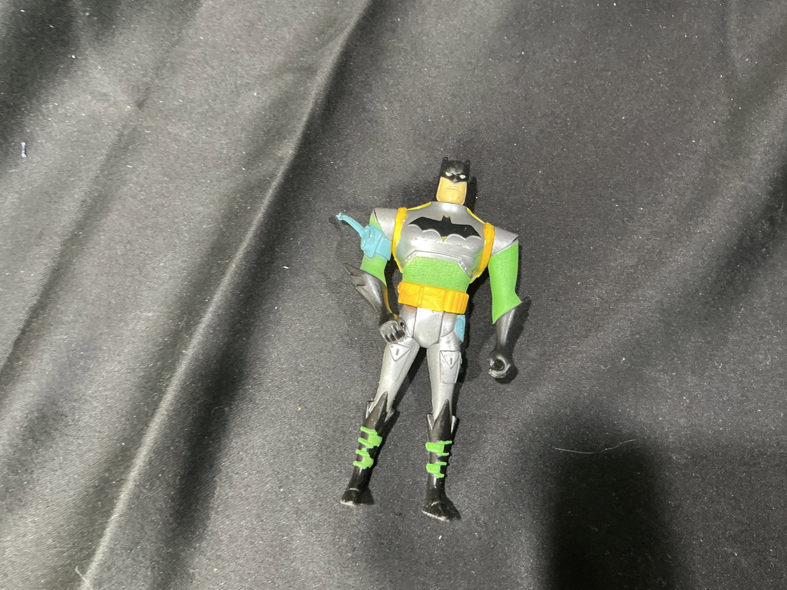 DC Batman Green Armor Figure: Returning after a long absence, this DC Comics Batman action figure by Mattel features a silver and black suit with bright green arms, a yellow utility belt, yellow armored backpack detail, and a
