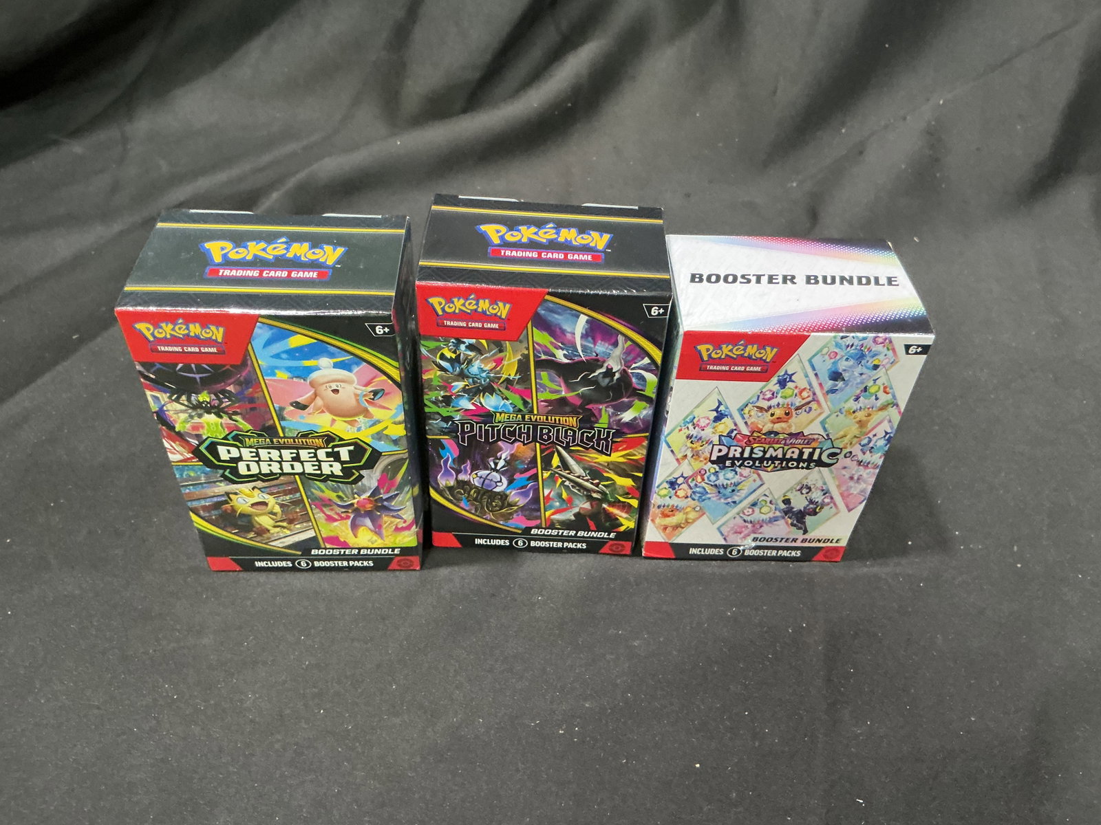 Perfect Order, Pitch Black & Prismatic Evolutions Bundles: Another opportunity in this auction, this factory sealed Pokemon booster bundle trio combines Mega Evolution Perfect Order, Mega Evolution Pitch Black, and Scarlet & Violet Prismatic Evolutions.