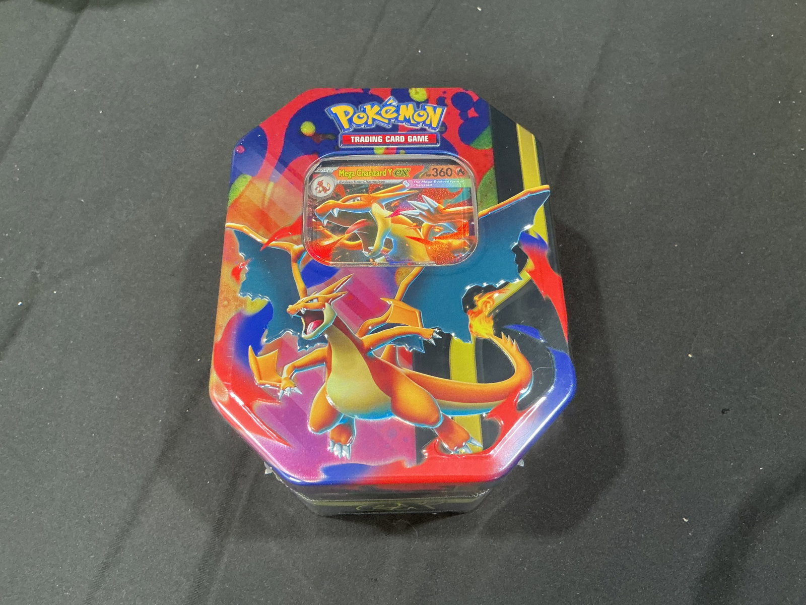 Mega Charizard Pokemon Tin Sealed: Returning for its second appearance in our auctions, this factory sealed Pokemon Mega Charizard collectible tin includes a Mega Charizard promo card, four Pokemon TCG booster packs, and a code card
