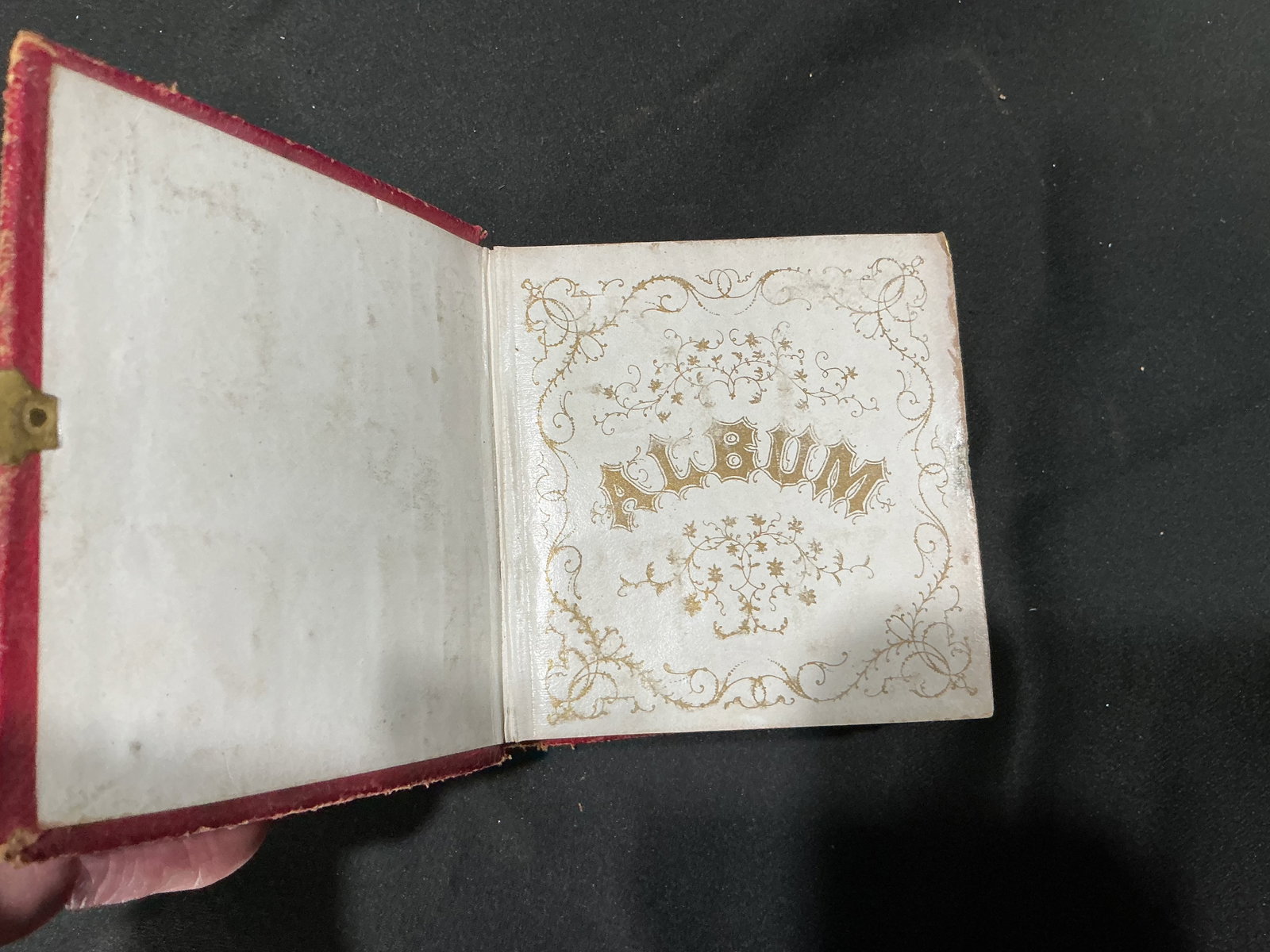 Antique Victorian Red Photo Album: Offered again after its previous appearance, this antique red leather Victorian photo album features a decorative clasp, multiple tintype portraits, and ornate gilt interior pages. A distinctive