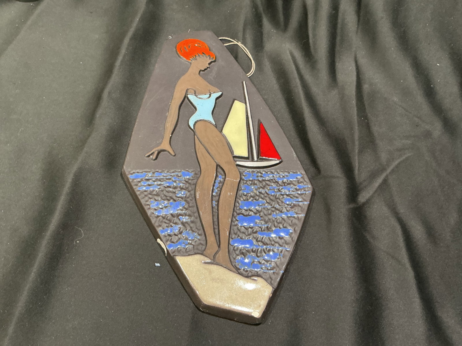 Vintage Norwegian Ceramic Plaque: Featured again after appearing in a previous auction, this vintage 1960s Norwegian ceramic wall plaque depicts a beachside figure with a sailboat and stylized coastal scene. Marked 'Made in Norway'