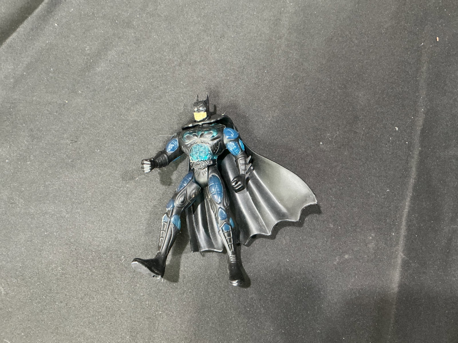Batman Armored Blue & Black Figure: Making another appearance, this DC Comics Batman action figure features an armored blue and black suit with a molded cape and articulated limbs. Likely inspired by a modern tactical or futuristic