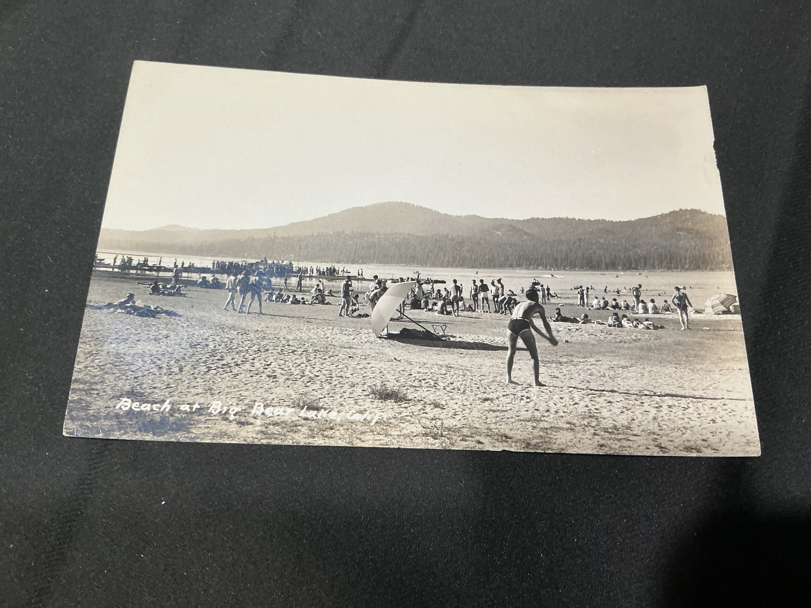 Vintage Big Bear Lake California Postcard - Beach Scene: Capturing a lively Southern California mountain resort scene, this vintage black-and-white postcard is titled "Beach at Big Bear Lake, Calif." and depicts a busy lakeside beach with bathers and a