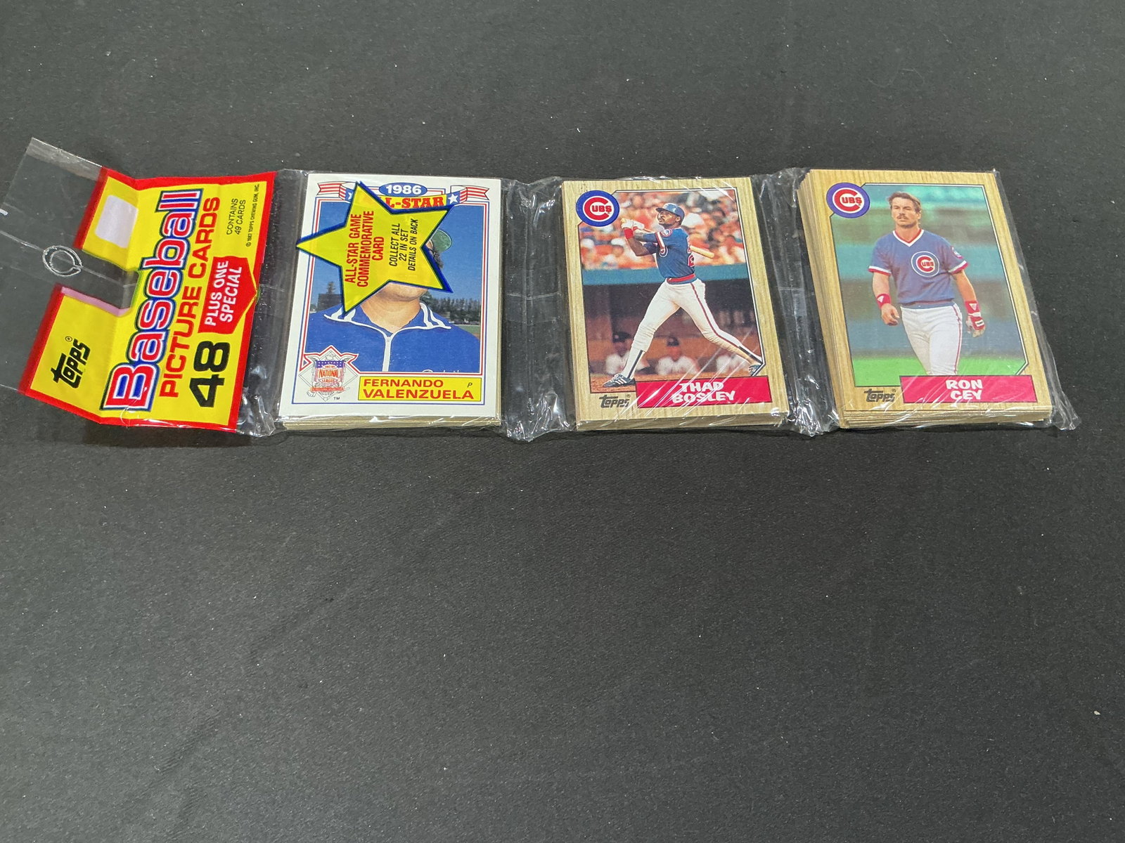 1986 Topps Baseball 48-Card Rack Pack: A vintage 1986 Topps Baseball rack pack containing 48 picture cards plus one special insert. Visible cards include Fernando Valenzuela, Thad Bosley, and Ron Cey, with the original multi-section
