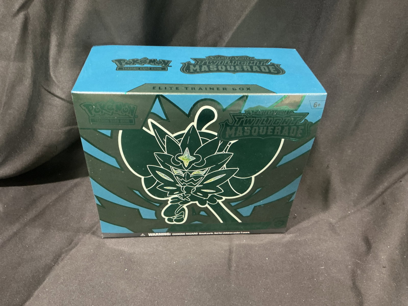 Pokemon Twilight Masquerade Ogerpon ETB Sealed: Featured once more, this factory sealed Pokemon Scarlet & Violet Twilight Masquerade Elite Trainer Box showcases Teal Mask Ogerpon artwork and includes booster packs, a promo card, sleeves, dice, mark