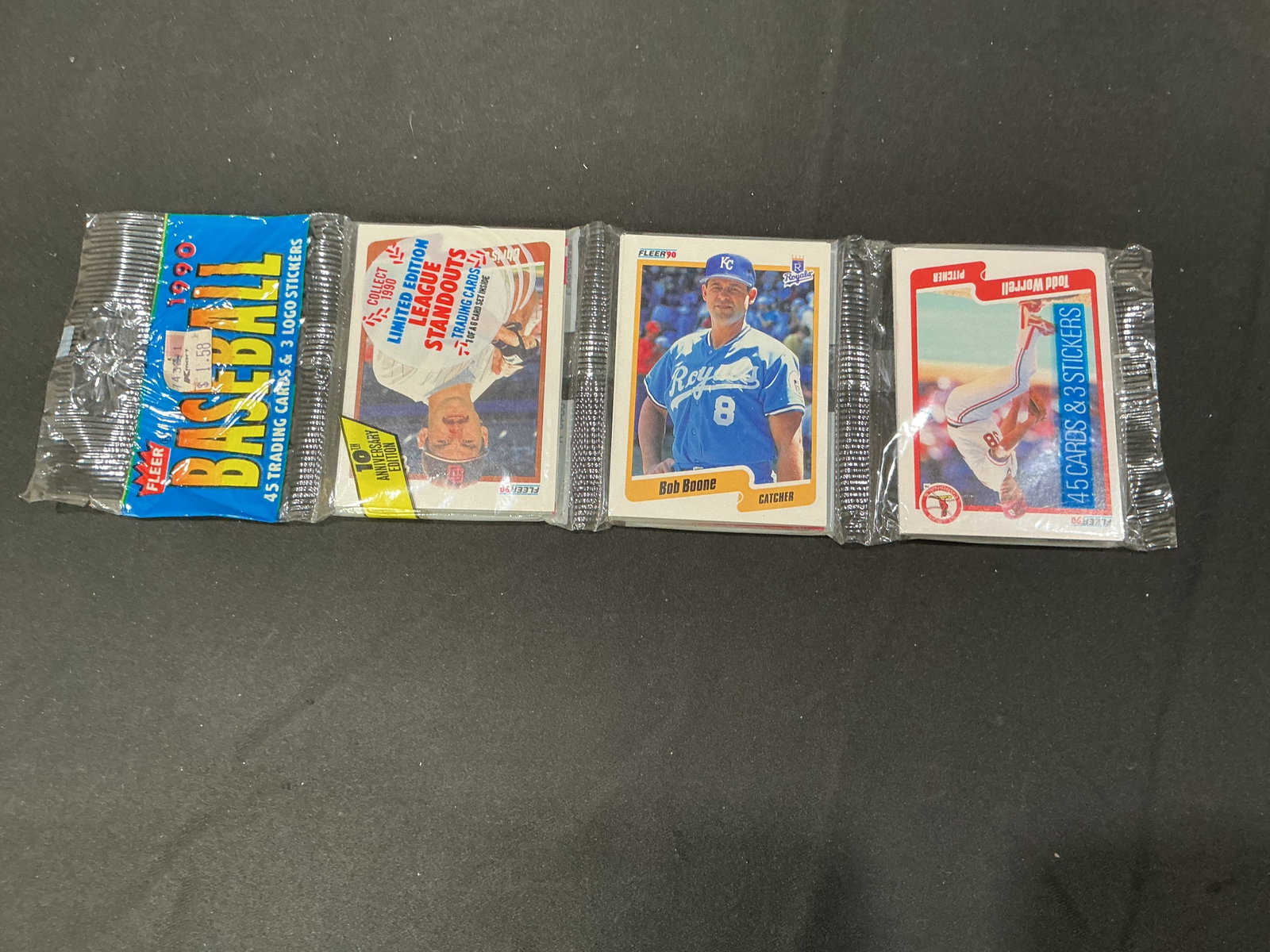 1990 Fleer Baseball 45-Card Rack Pack: Vintage 1990 Fleer Baseball rack pack containing 45 trading cards plus three logo stickers in the original three-section packaging. Visible cards include the limited-edition League Standouts insert,