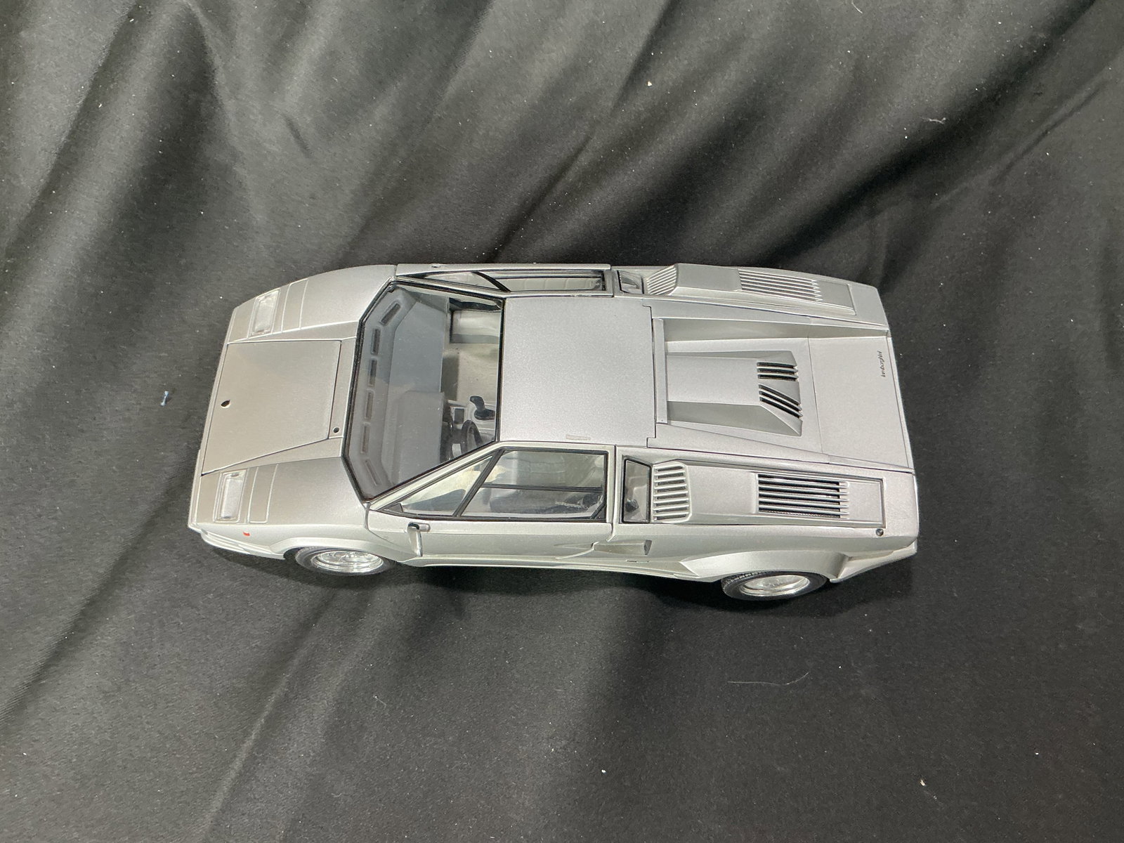 Lamborghini Countach 1:18 Die-Cast Model: Returning for another opportunity, this detailed 1:18 scale die-cast Lamborghini Countach model is finished in silver and features opening doors, a detailed interior, visible engine components, and