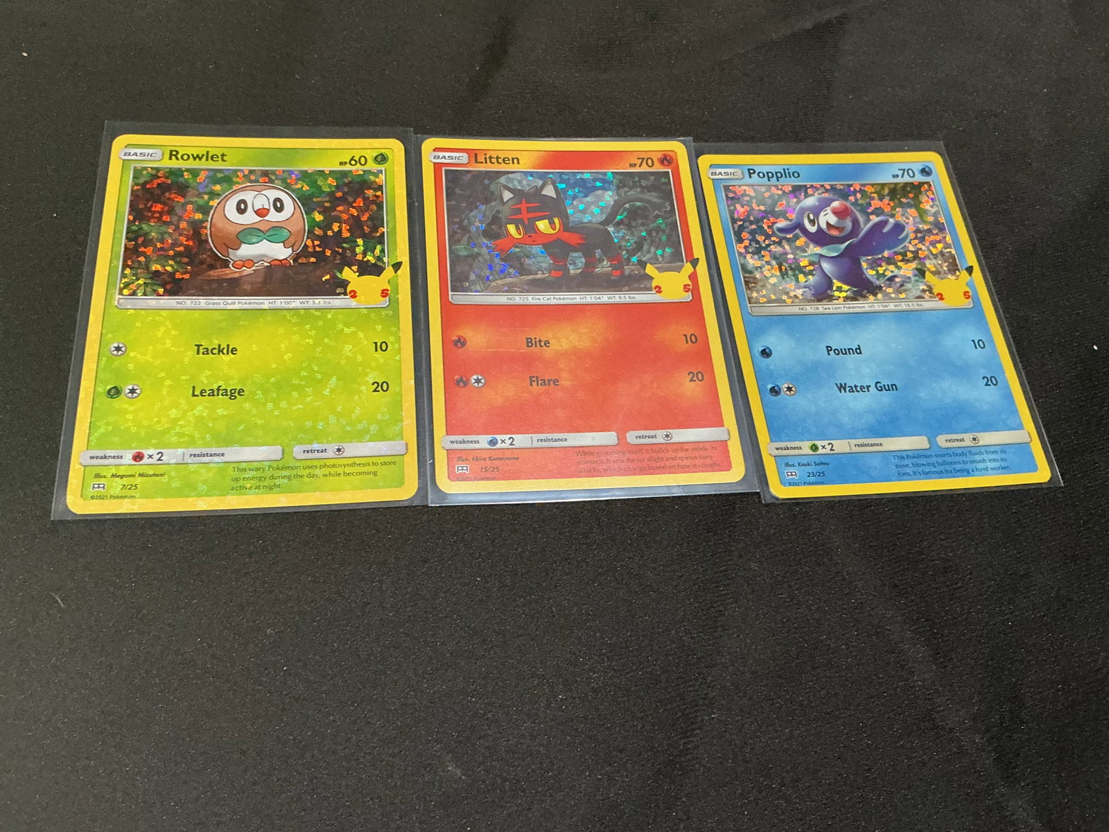 Pokemon 25th Holo Rowlet Litten Popplio Trio: Pokemon 25th Anniversary McDonald's three-card holo starter grouping featuring Rowlet #7/25, Litten #15/25, and Popplio #23/25. All three feature the distinctive confetti-style holographic backgrounds