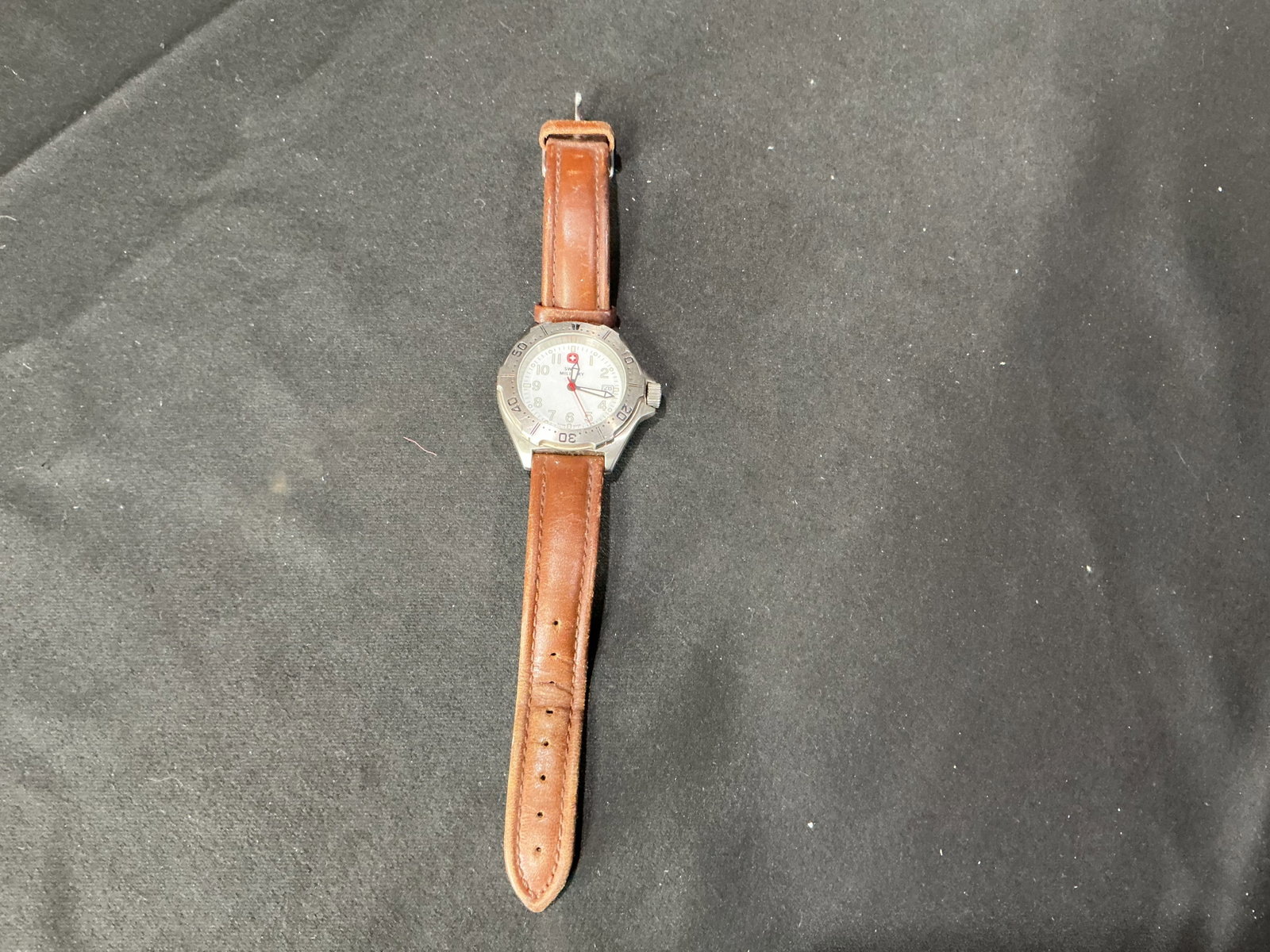 Swiss Military Stainless Steel Quartz Wristwatch: Offered again with classic Swiss styling, this Swiss Military stainless steel wristwatch features a silver dial with Arabic numerals, luminous hour markers, a date window at 3 o'clock, rotating