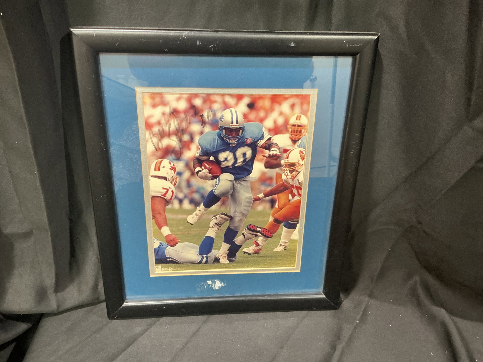 Barry Sanders Autographed Detroit Lions Framed Photo: Offered again for Detroit Lions and NFL collectors, this framed color photograph is signed by Hall of Fame running back Barry Sanders in black marker. Featuring Sanders in action during his playing ca