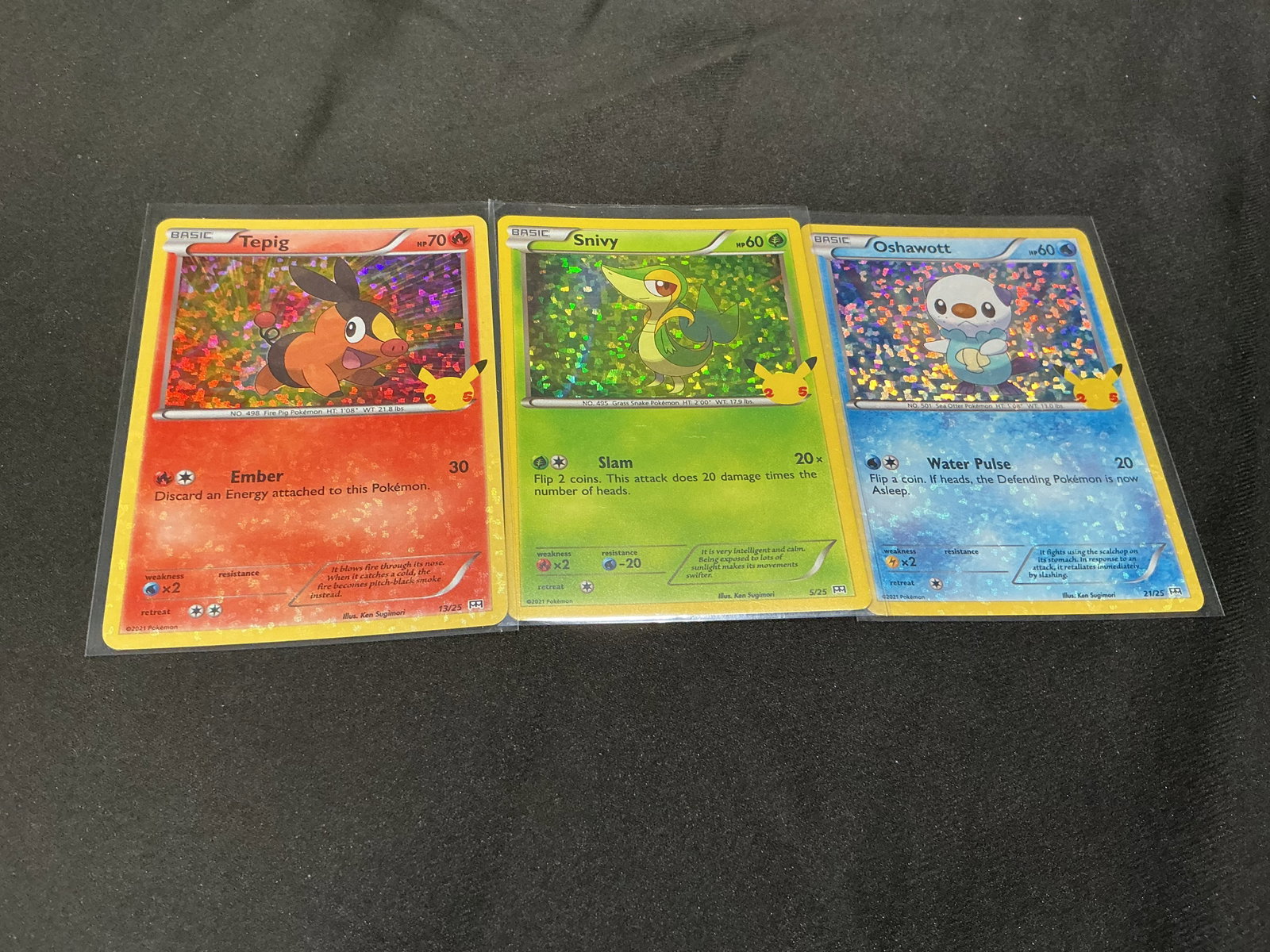 Pokemon McDonald's 25th Holo Starter Trio: Pokemon 25th Anniversary McDonald's holographic card trio featuring Tepig #13/25, Snivy #5/25, and Oshawott #21/25. All three cards feature the distinctive confetti-style holographic pattern and