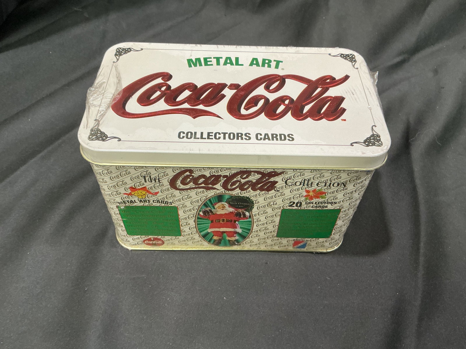 Coca-Cola Metal Art Collector Cards Tin: Coca-Cola Metal Art Collectors Cards tin featuring classic Coca-Cola branding and a Santa Claus holiday design. The decorative metal container was produced for a collectible card series and presents