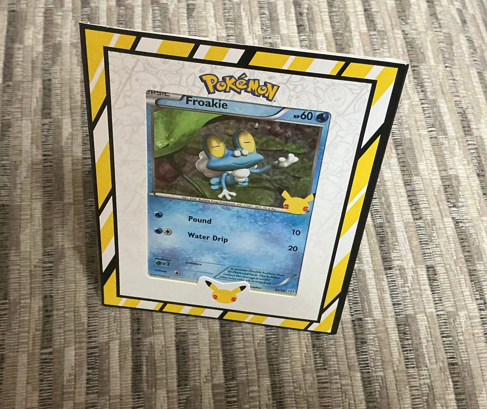 Pokemon Froakie 25th Anniversary Display Card: Pokemon 25th Anniversary display piece featuring Froakie #22/25 mounted in a freestanding Pokemon-themed presentation frame. The card features the Pikachu 25th Anniversary stamp and is displayed