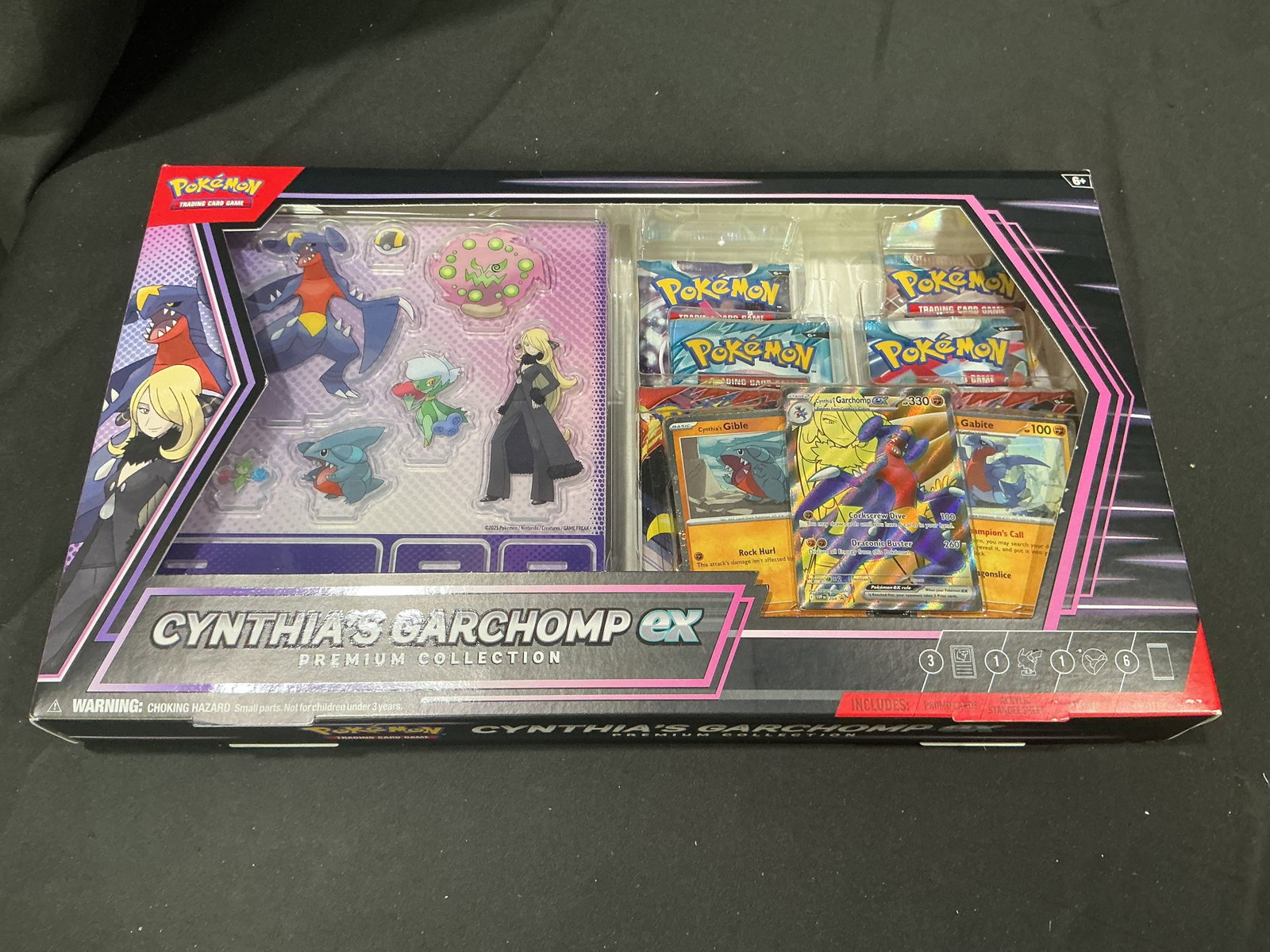Pokemon Cynthia's Garchomp ex Premium Collection: Making its first auction appearance, this factory sealed Pokemon TCG Cynthia's Garchomp ex Premium Collection features Cynthia and her signature Garchomp, with three visible promo cards including Cynt
