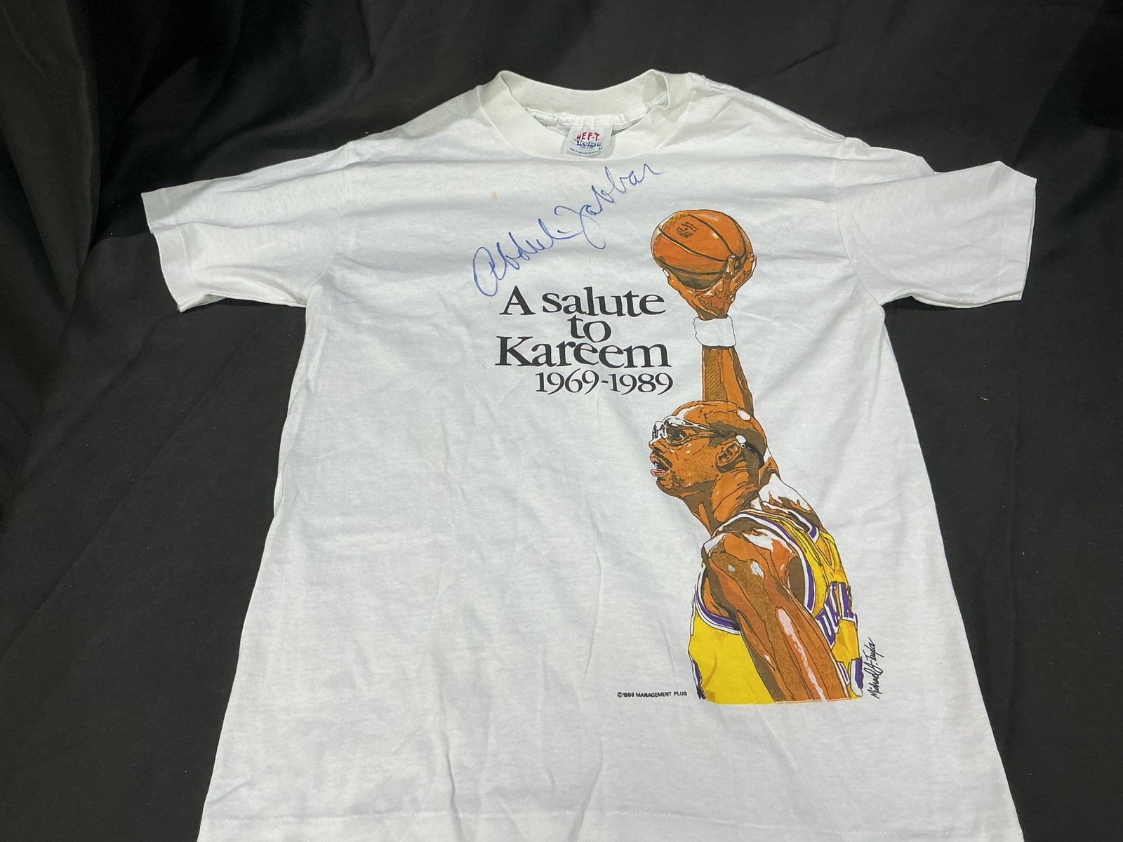 Kareem Abdul-Jabbar Signed 1989 Retirement Tribute T-Shirt: A standout first-time offering, this vintage white 'A Salute to Kareem 1969-1989' T-shirt commemorates the close of Kareem Abdul-Jabbar's legendary 20-season NBA career. The front features an illustra