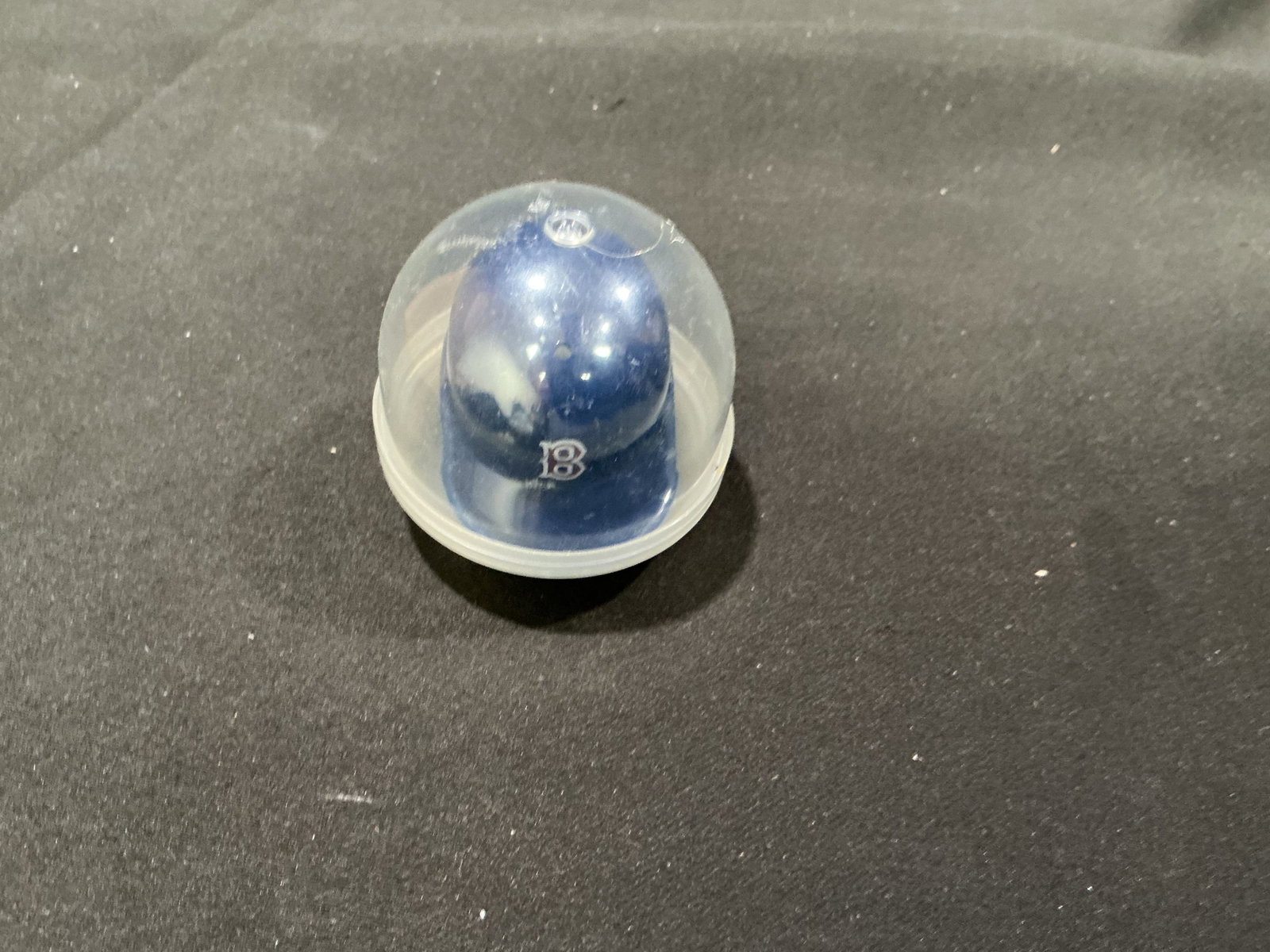 Boston Red Sox Mini Batting Helmet in Capsule: A compact Boston Red Sox baseball collectible featuring a navy blue miniature batting helmet with the classic red-and-white "B" logo on the front. The helmet remains housed inside its clear plastic di