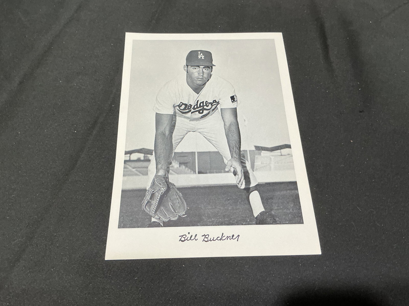 Bill Buckner Los Angeles Dodgers Black & White Photo: A vintage-style black and white baseball photograph features Bill Buckner in a Los Angeles Dodgers uniform posed on the field. Buckner's facsimile signature is printed beneath the image, creating a