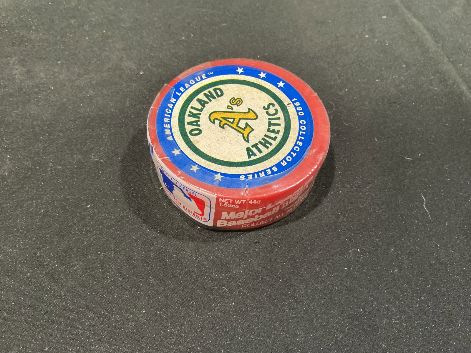 1990 Oakland Athletics Collector Series Baseball Tin: Celebrating the Oakland Athletics, this 1990 American League Collector Series Major League Baseball collectible is presented in a round team-logo tin with classic green-and-gold A's graphics. The peri