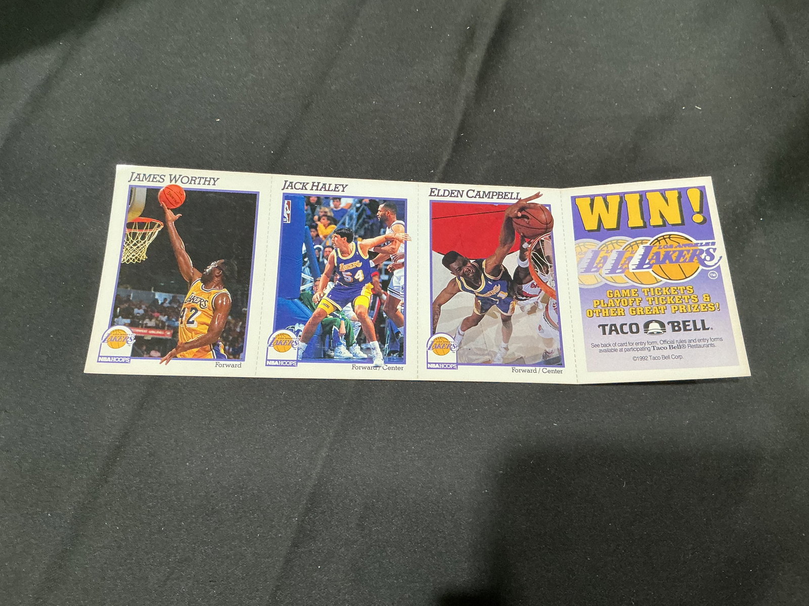 1992 NBA Hoops Lakers Taco Bell Uncut Strip James Worthy: Returning as an unusual Los Angeles Lakers promotional piece, this 1992 NBA Hoops uncut perforated strip features Hall of Famer James Worthy alongside Jack Haley and Elden Campbell, plus a Taco Bell L