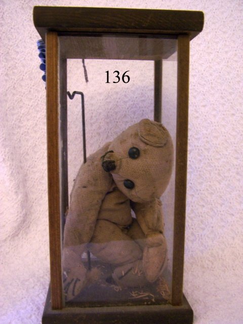 German Teddy Bear: German Teddy Bear – with straw stuffing – very old and well loved – stuffing coming out in places that is why it is inside a small showcase